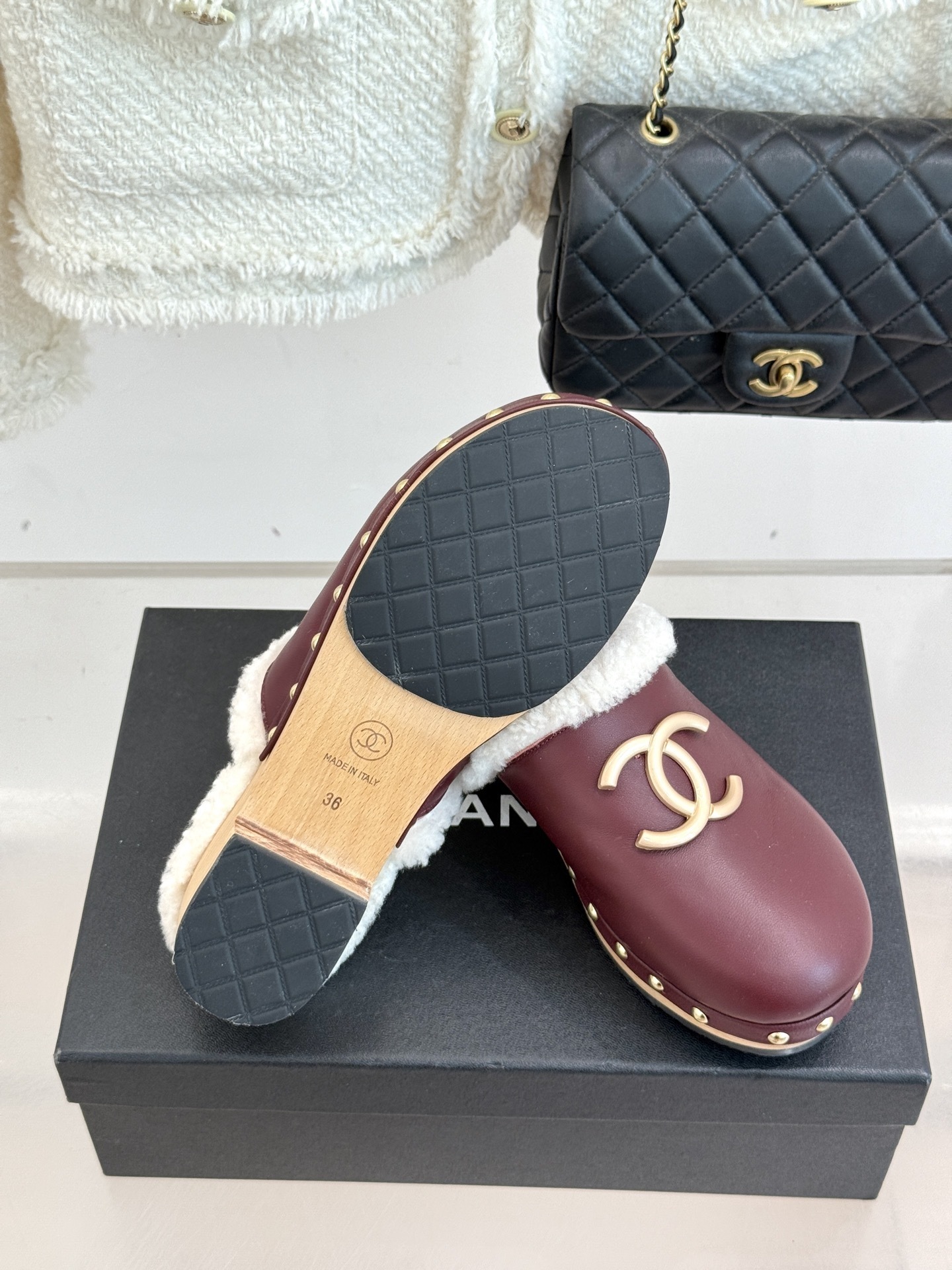 Pair of burgundy Chanel leather clogs with white shearling lining and gold CC logo on a black box - Hình 9