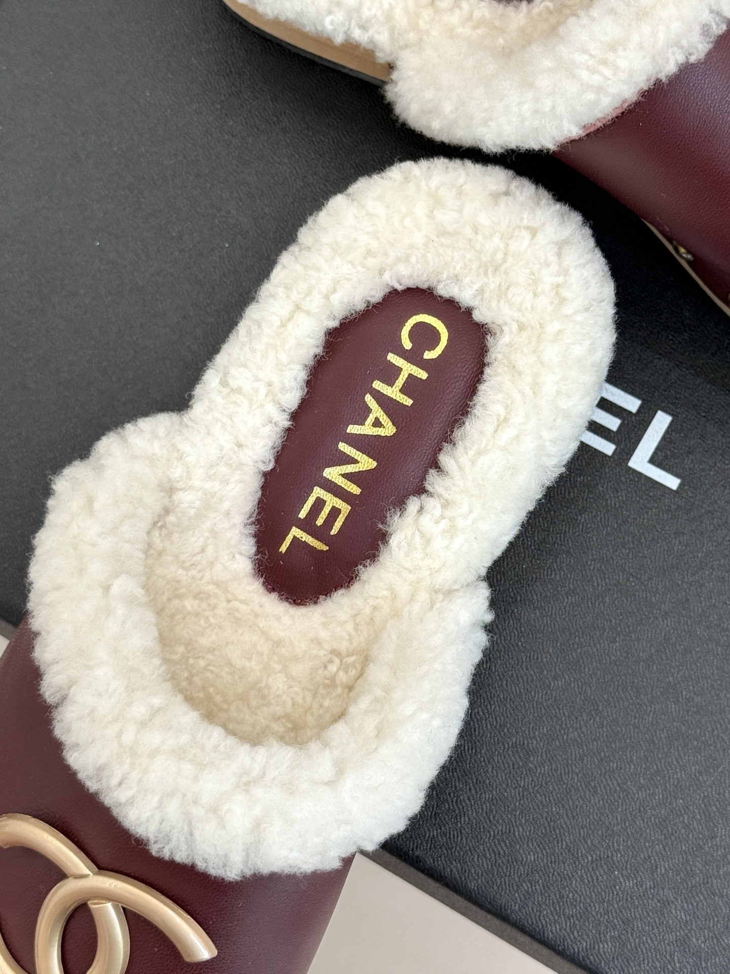Pair of burgundy Chanel leather clogs with white shearling lining and gold CC logo on a black box - Hình 8