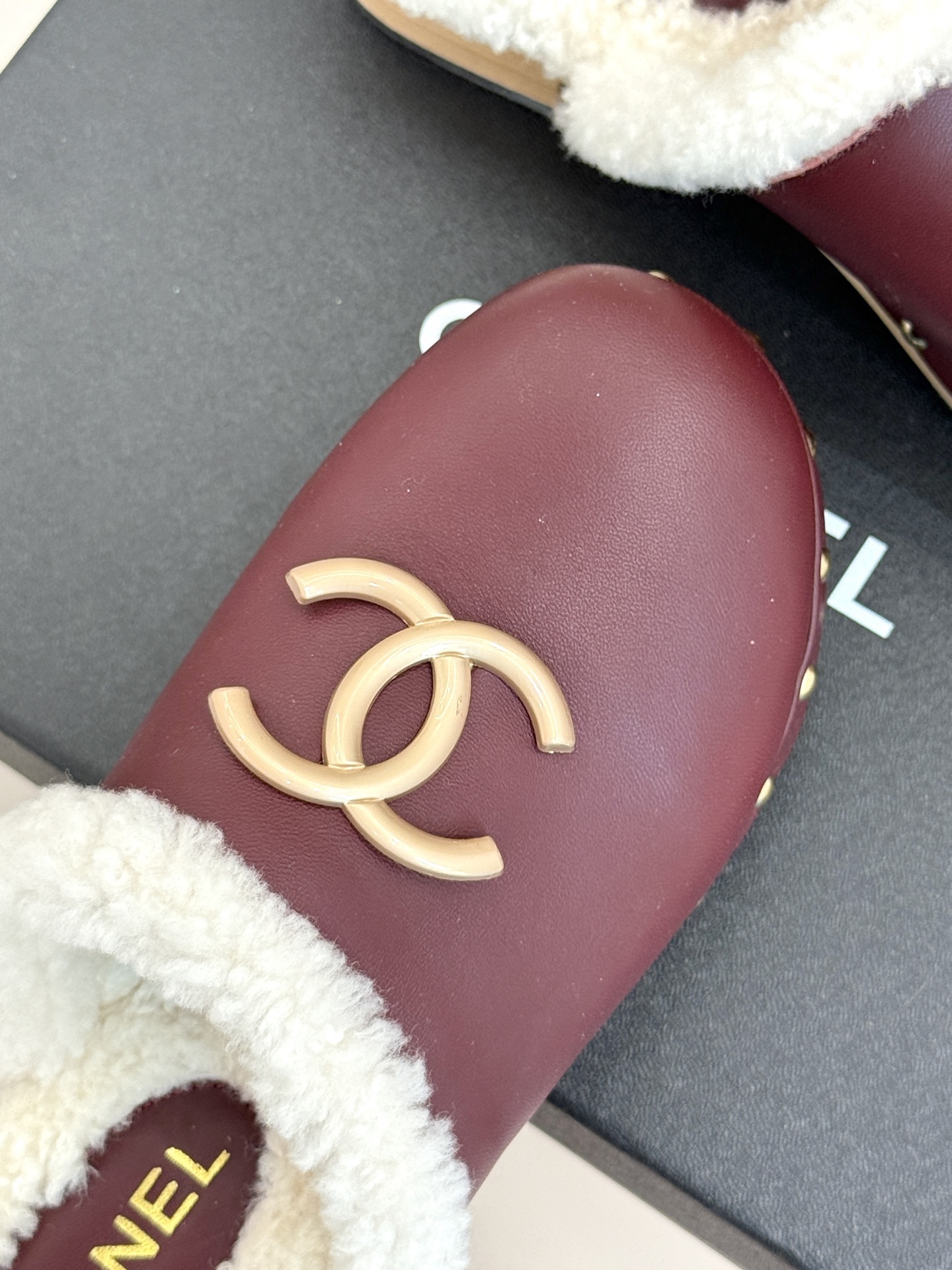 Pair of burgundy Chanel leather clogs with white shearling lining and gold CC logo on a black box - Hình 7