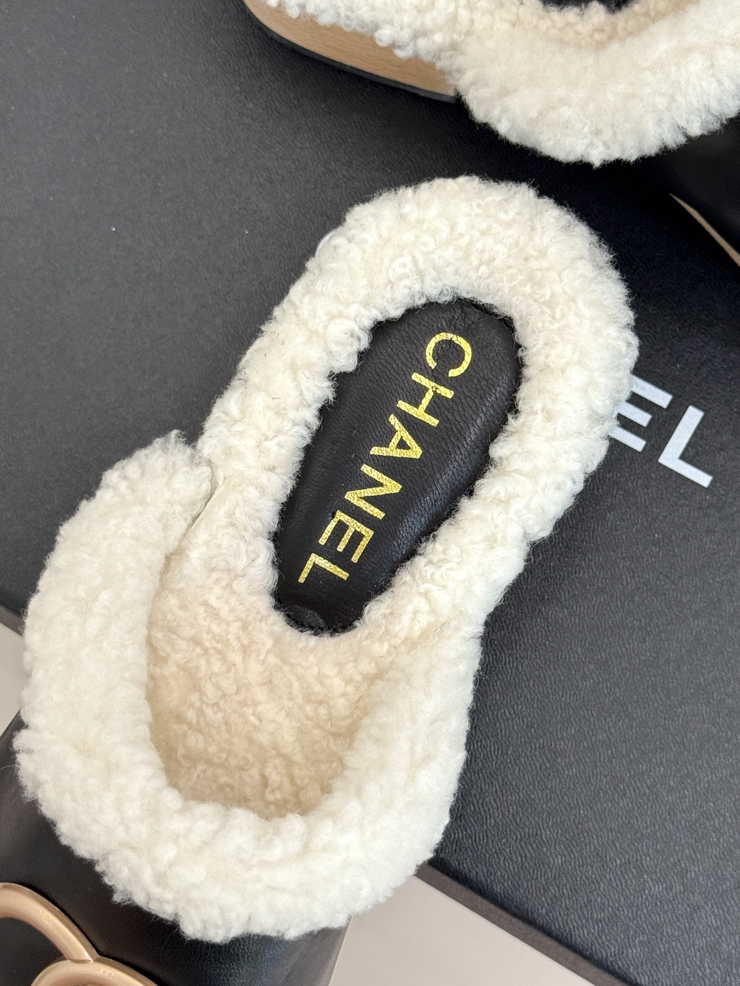 Pair of Chanel black leather clogs with white shearling lining, gold CC logo, and studded wooden soles resting on a black box - Hình 8