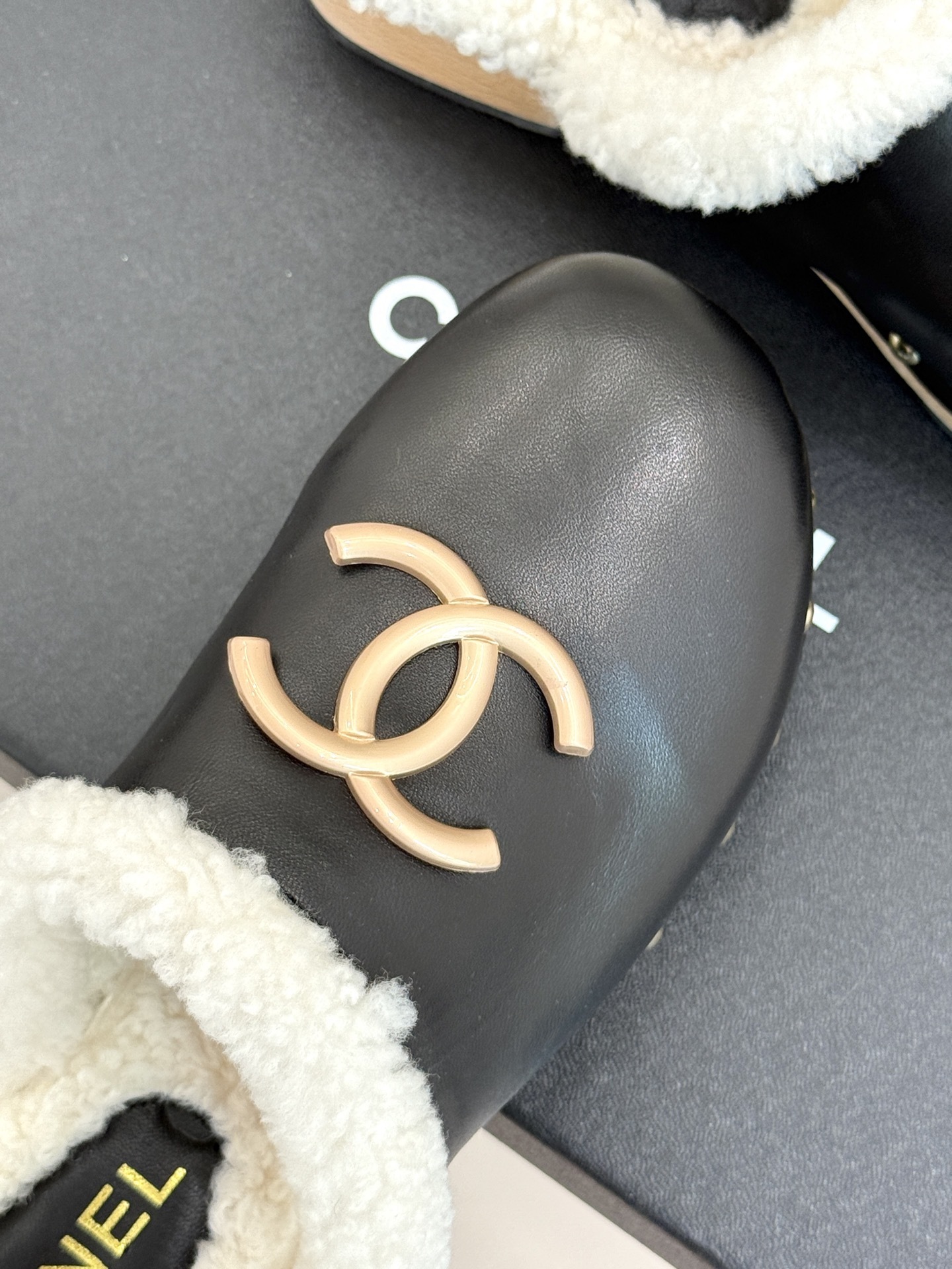 Pair of Chanel black leather clogs with white shearling lining, gold CC logo, and studded wooden soles resting on a black box - Hình 7