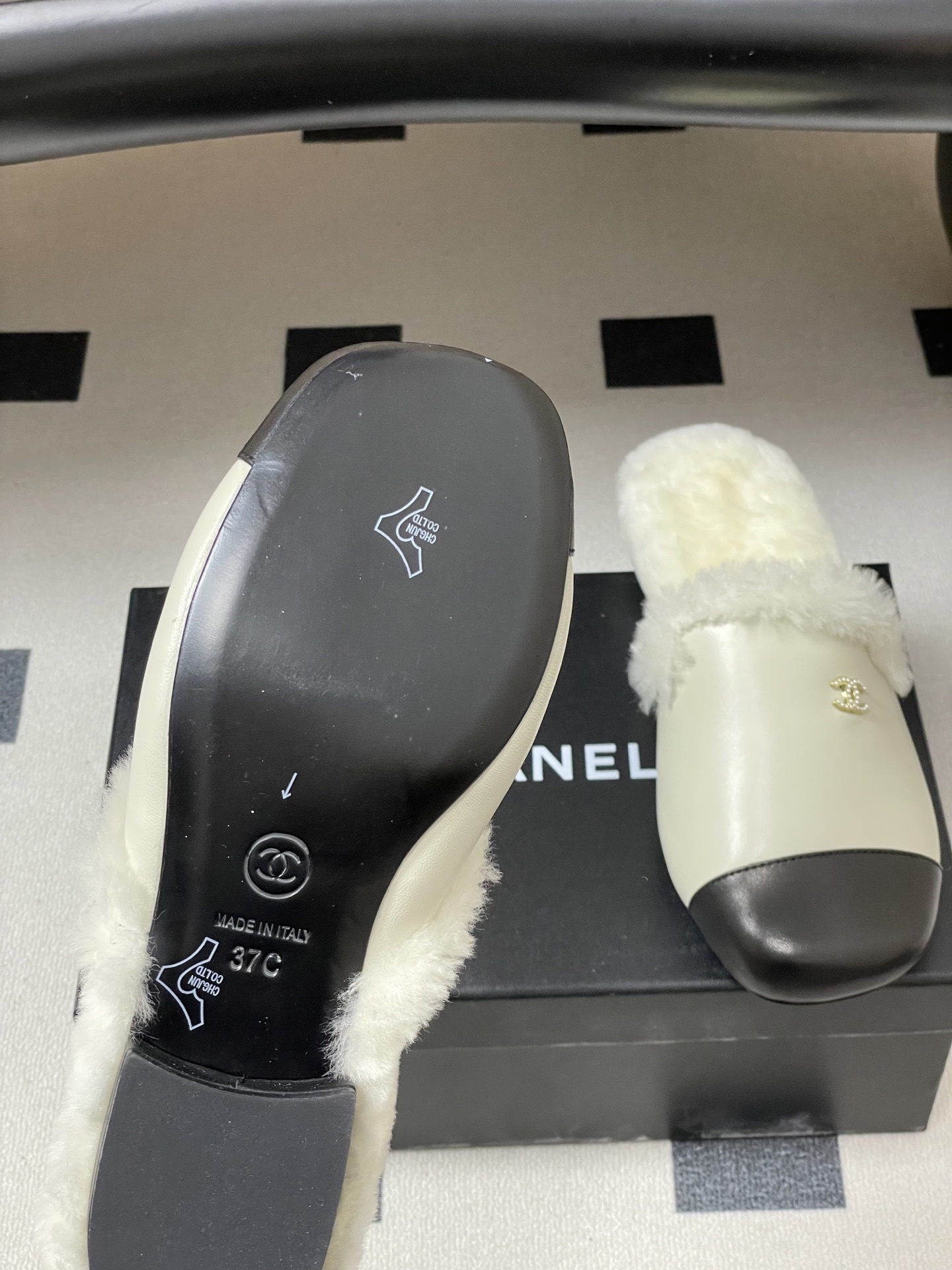 Luxury cream leather mules with black cap toe and white faux fur lining shown on a black surface. - Hình 8