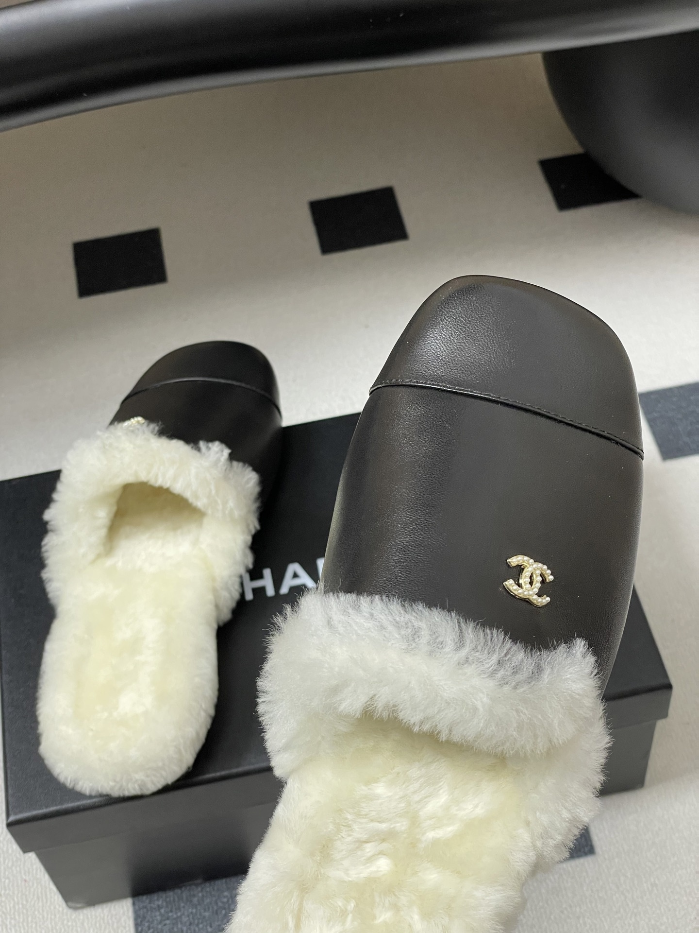 Pair of black leather mules with white shearling lining and gold interlocking logo on a black surface - Hình 9