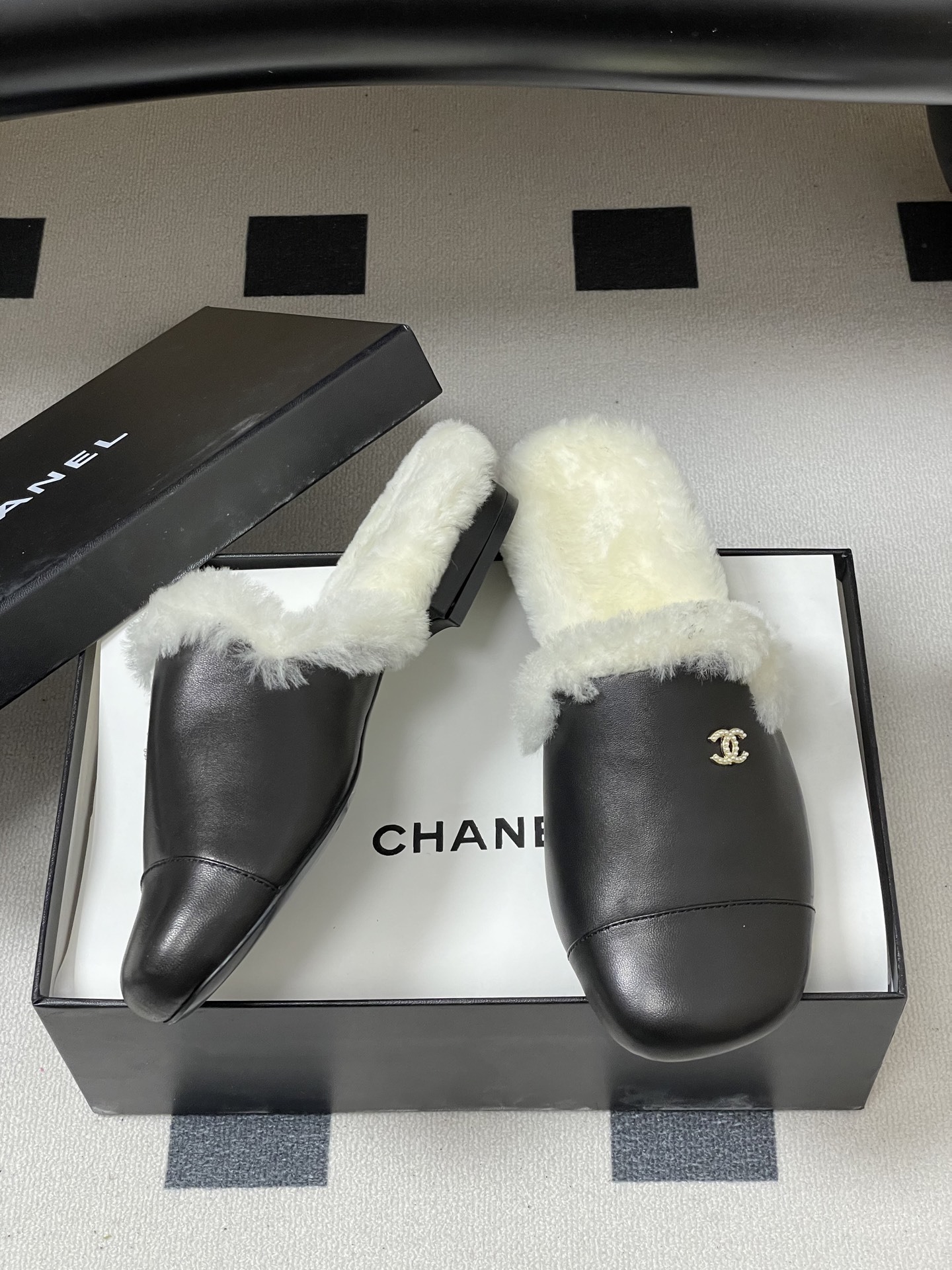 Pair of black leather mules with white shearling lining and gold interlocking logo on a black surface - Hình 6