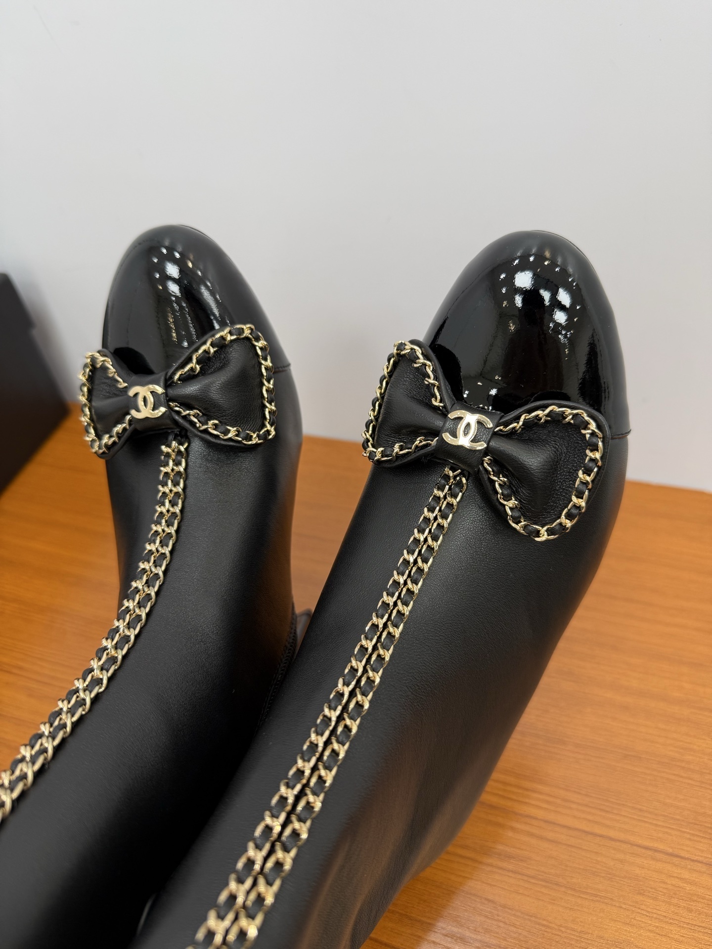 Pair of Chanel black leather ankle boots with patent toe caps, gold chain trim, and CC logo bows. - Hình 9