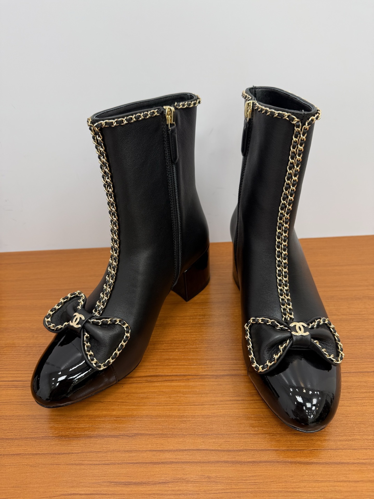 Pair of Chanel black leather ankle boots with patent toe caps, gold chain trim, and CC logo bows. - Hình 7