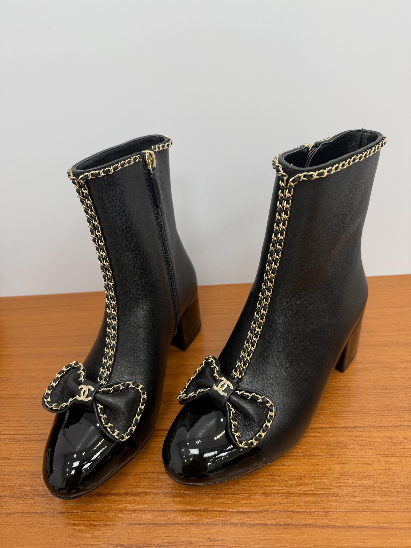 Pair of Chanel black leather ankle boots with patent toe caps, gold chain trim, and CC logo bows. - Hình 6
