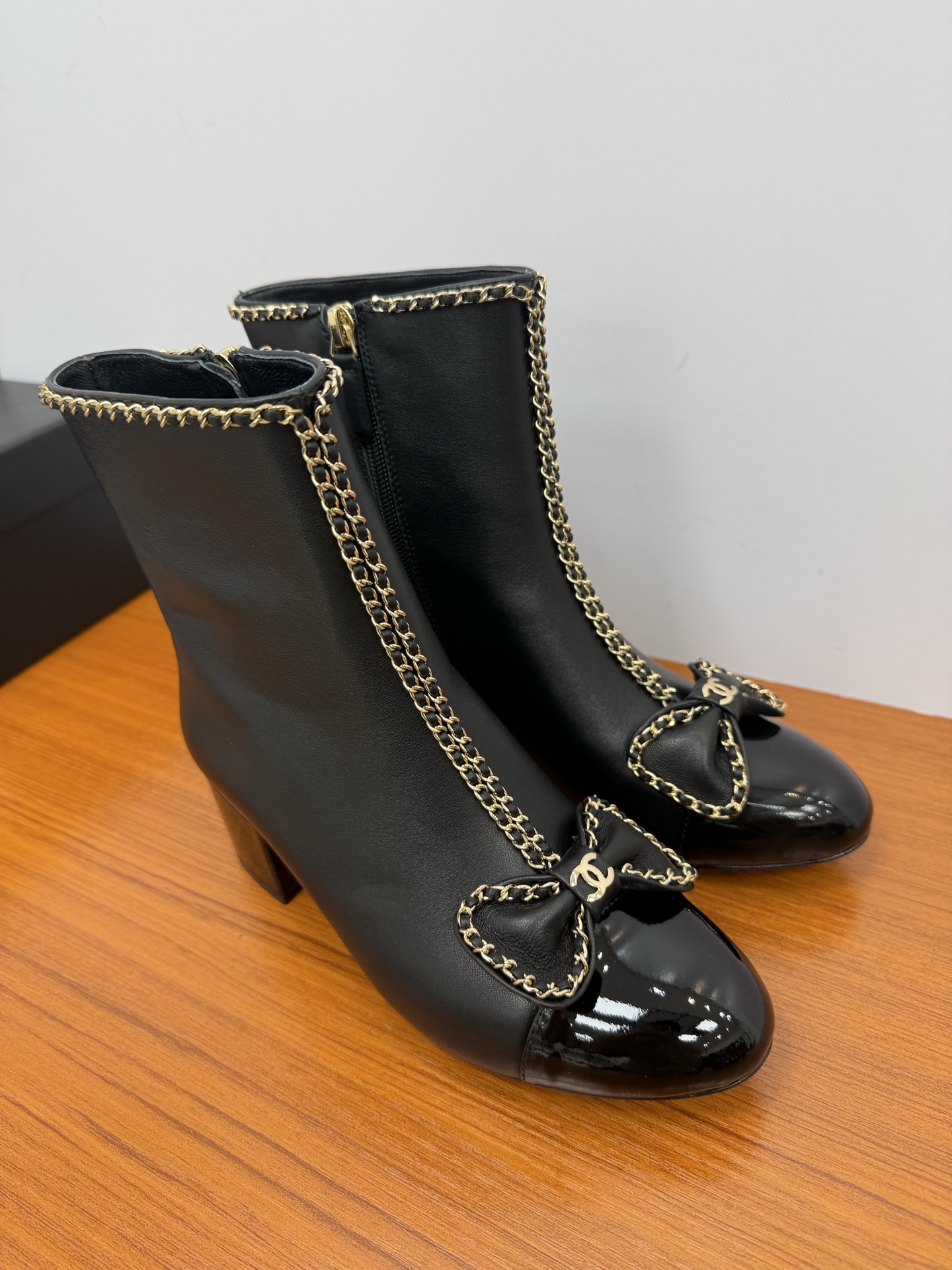 Pair of Chanel black leather ankle boots with patent toe caps, gold chain trim, and CC logo bows. - Hình 4