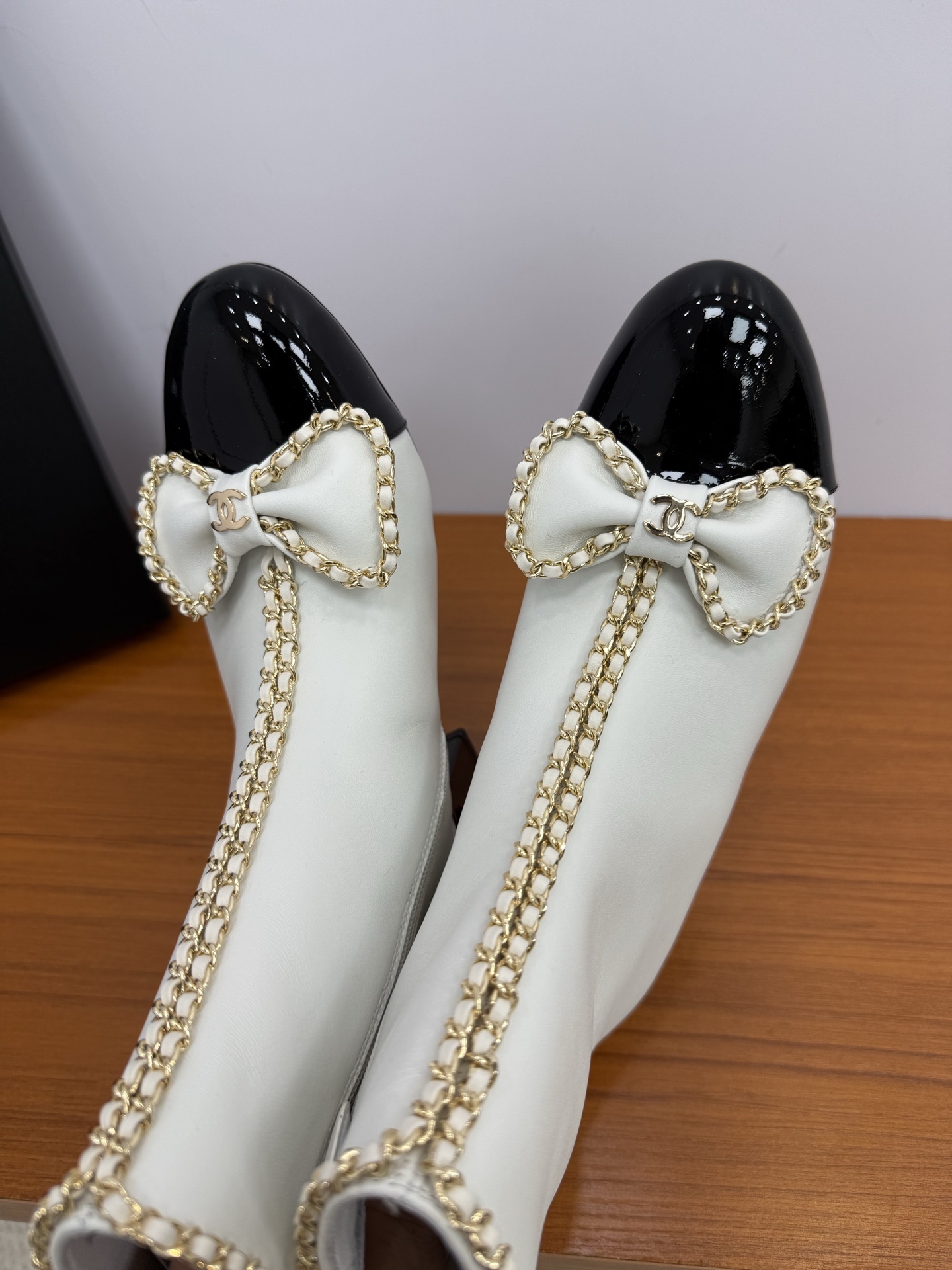 Elegant white leather ankle boots with black patent leather cap toe and gold chain trim with bow detail - Hình 9