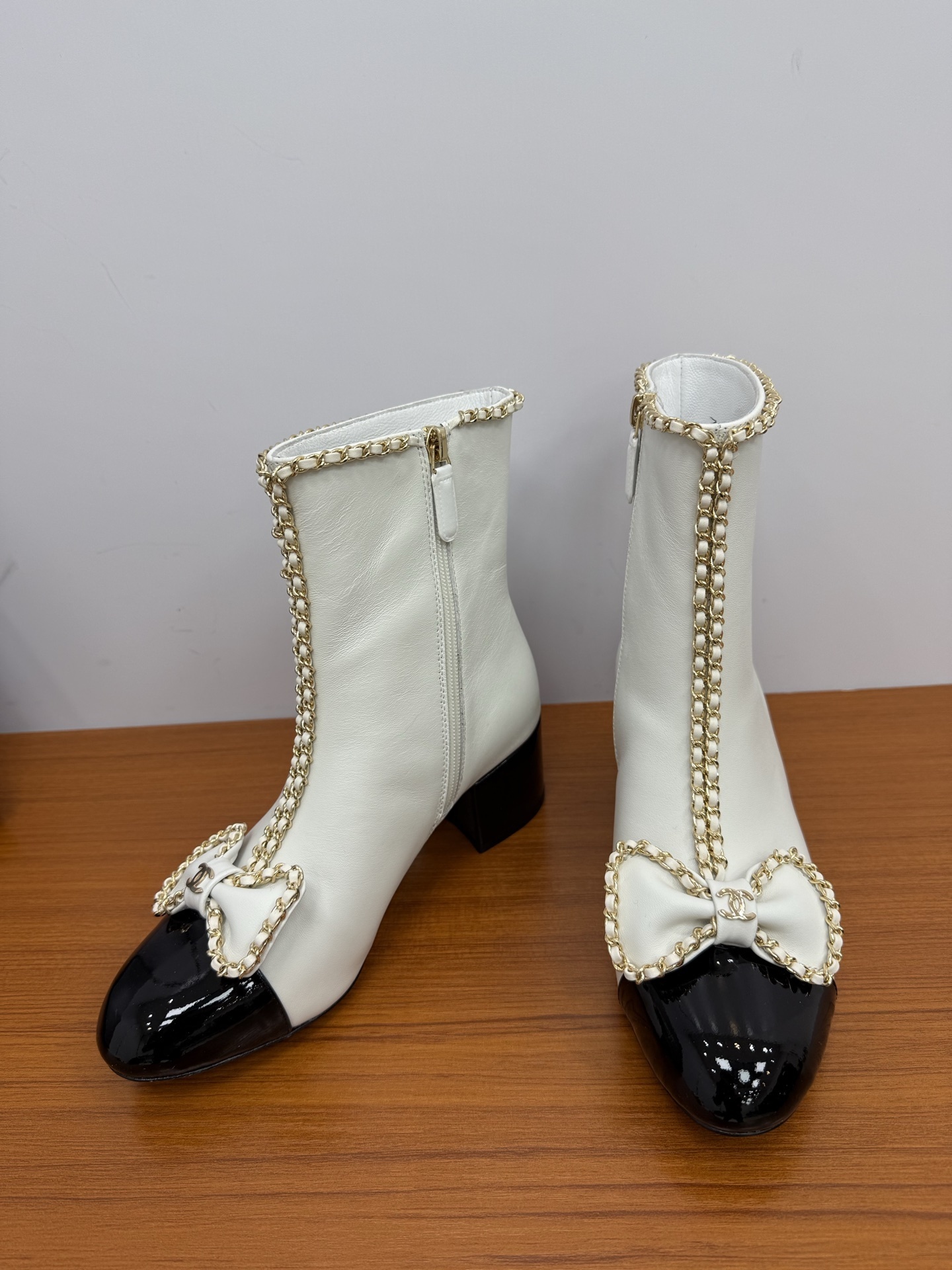 Elegant white leather ankle boots with black patent leather cap toe and gold chain trim with bow detail - Hình 7