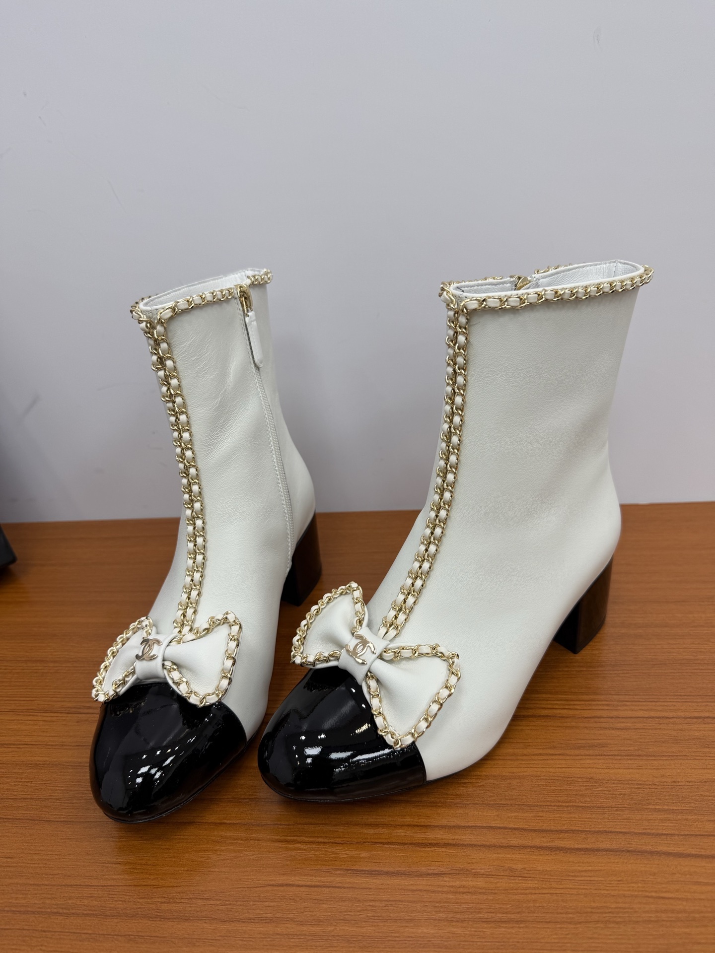 Elegant white leather ankle boots with black patent leather cap toe and gold chain trim with bow detail - Hình 6