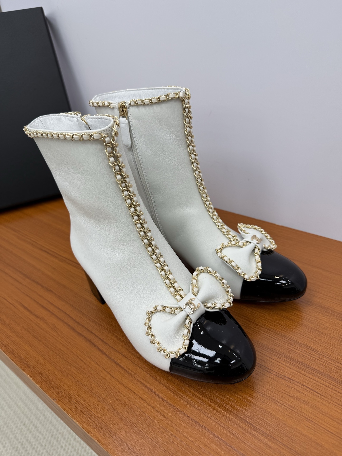 Elegant white leather ankle boots with black patent leather cap toe and gold chain trim with bow detail - Hình 4