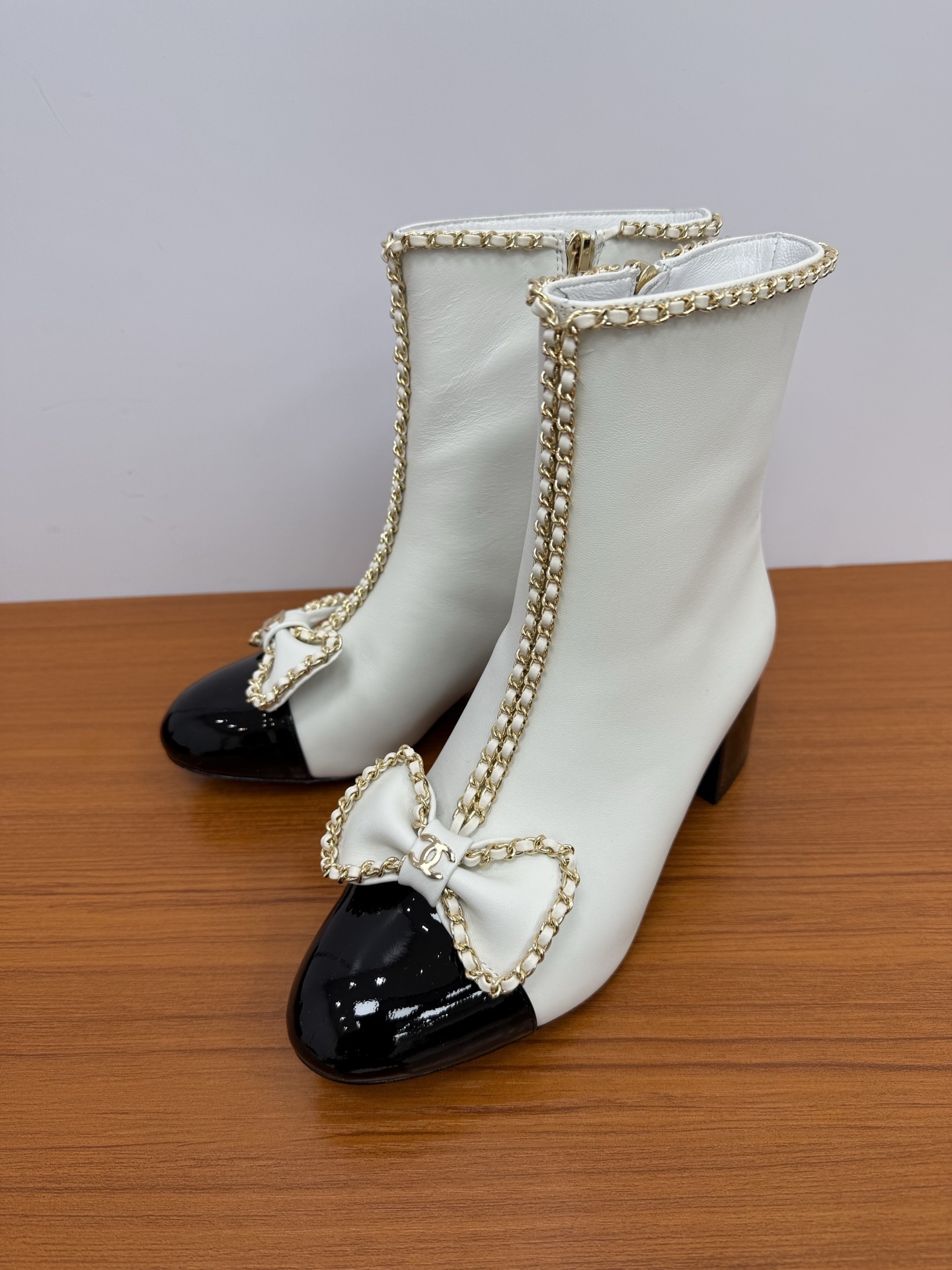 Elegant white leather ankle boots with black patent leather cap toe and gold chain trim with bow detail - Hình 3