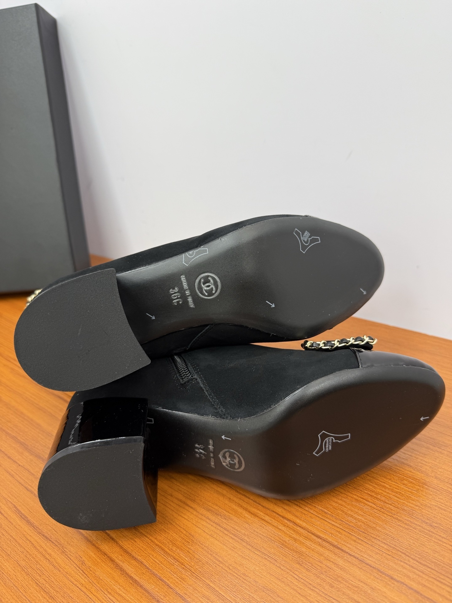 A pair of elegant black suede ankle boots with gold chain trim and a decorative bow on the patent leather toe cap. - Hình 8