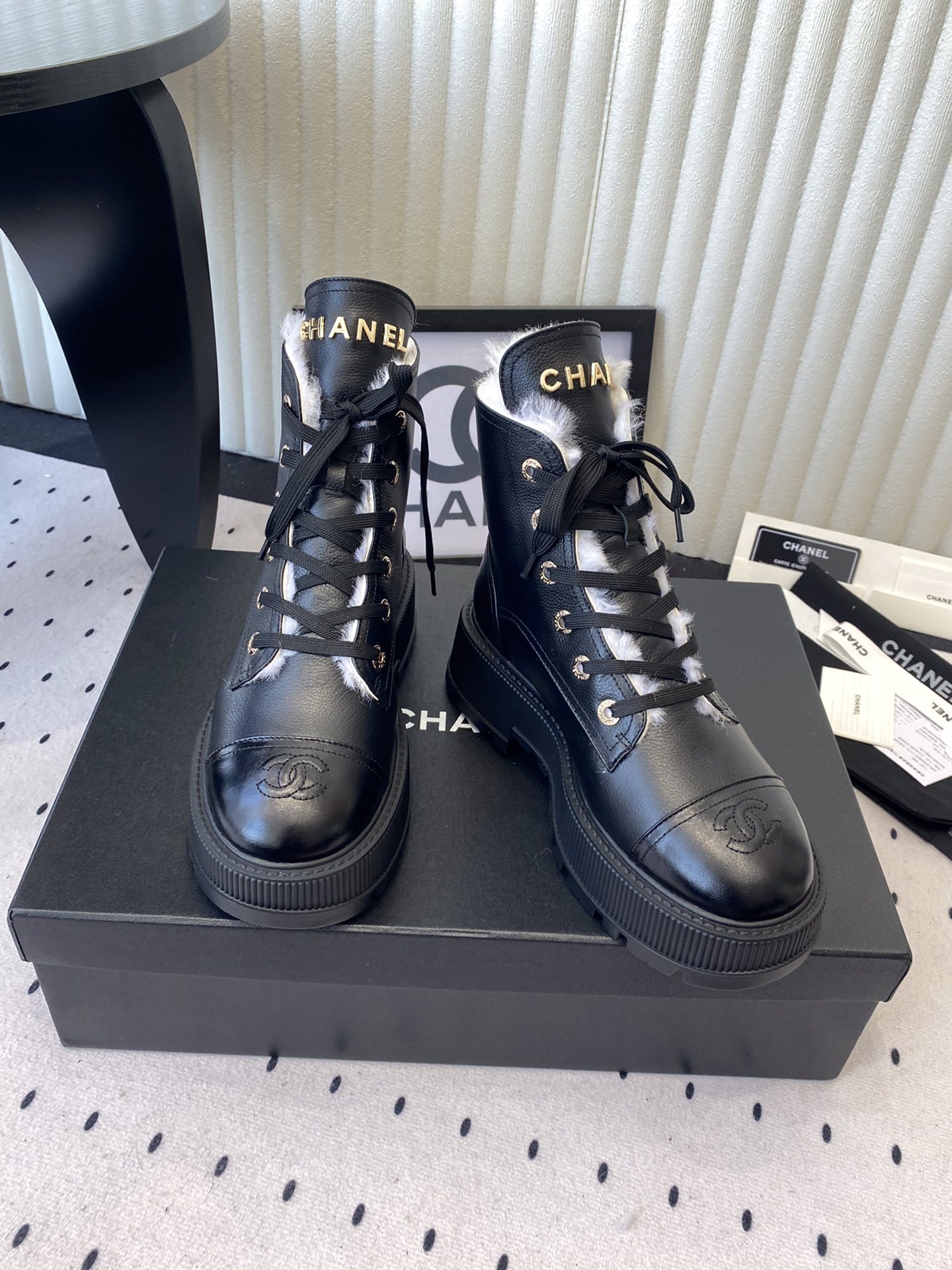 Chanel black leather lace-up combat boots with white shearling lining and gold-tone hardware on a black box. - Hình 7