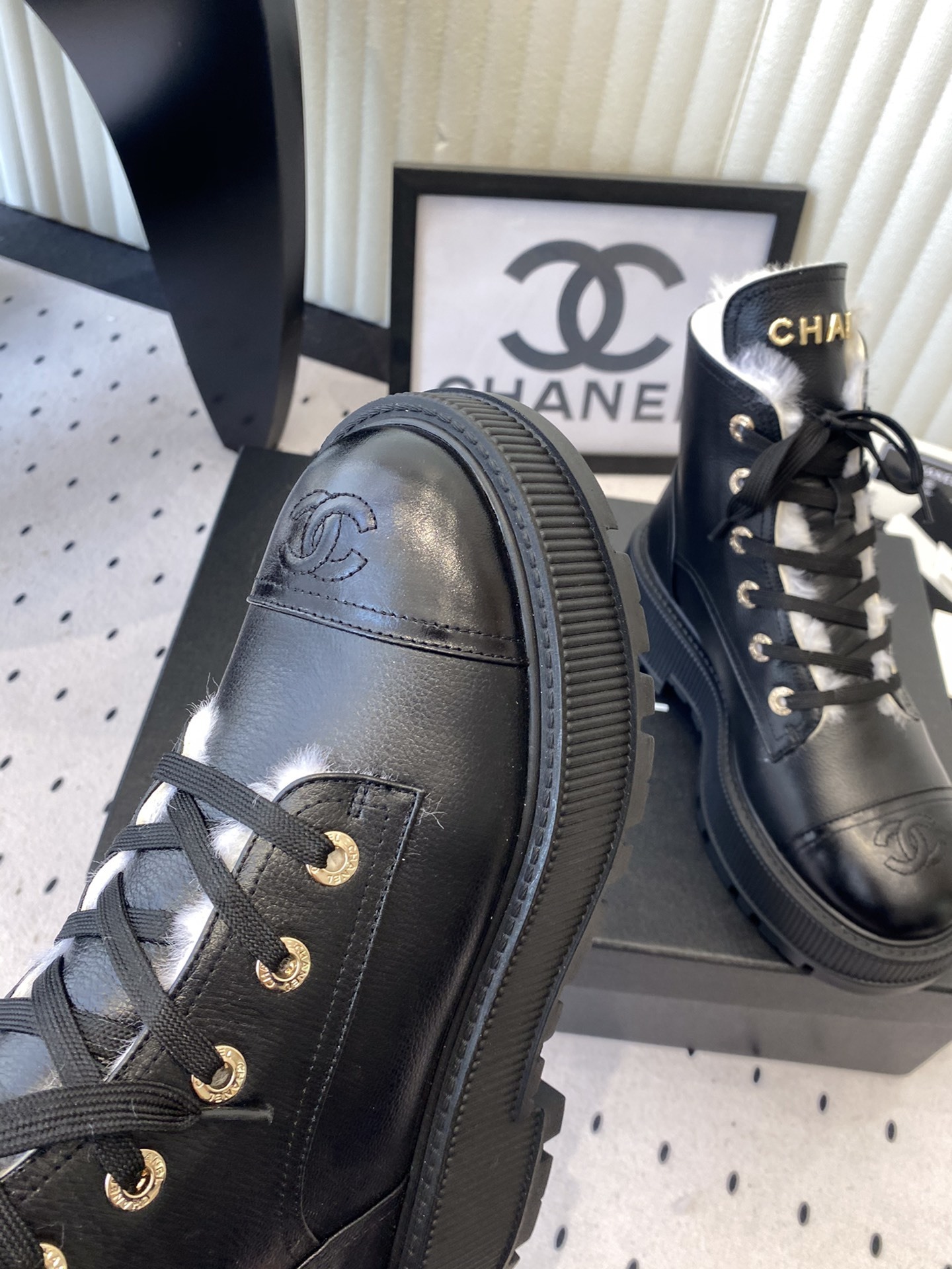 Chanel black leather lace-up combat boots with white shearling lining and gold-tone hardware on a black box. - Hình 6