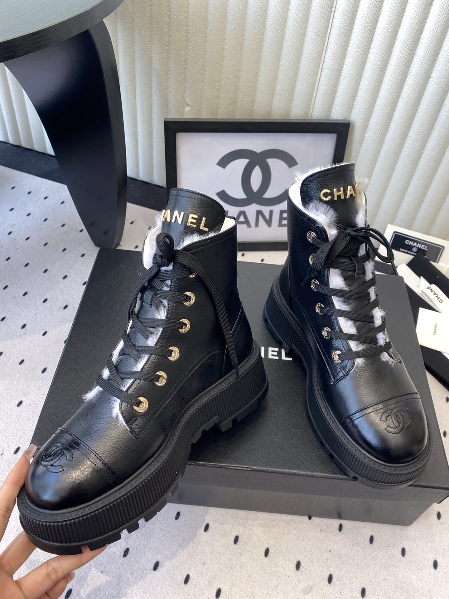 Chanel black leather lace-up combat boots with white shearling lining and gold-tone hardware on a black box. - Hình 5