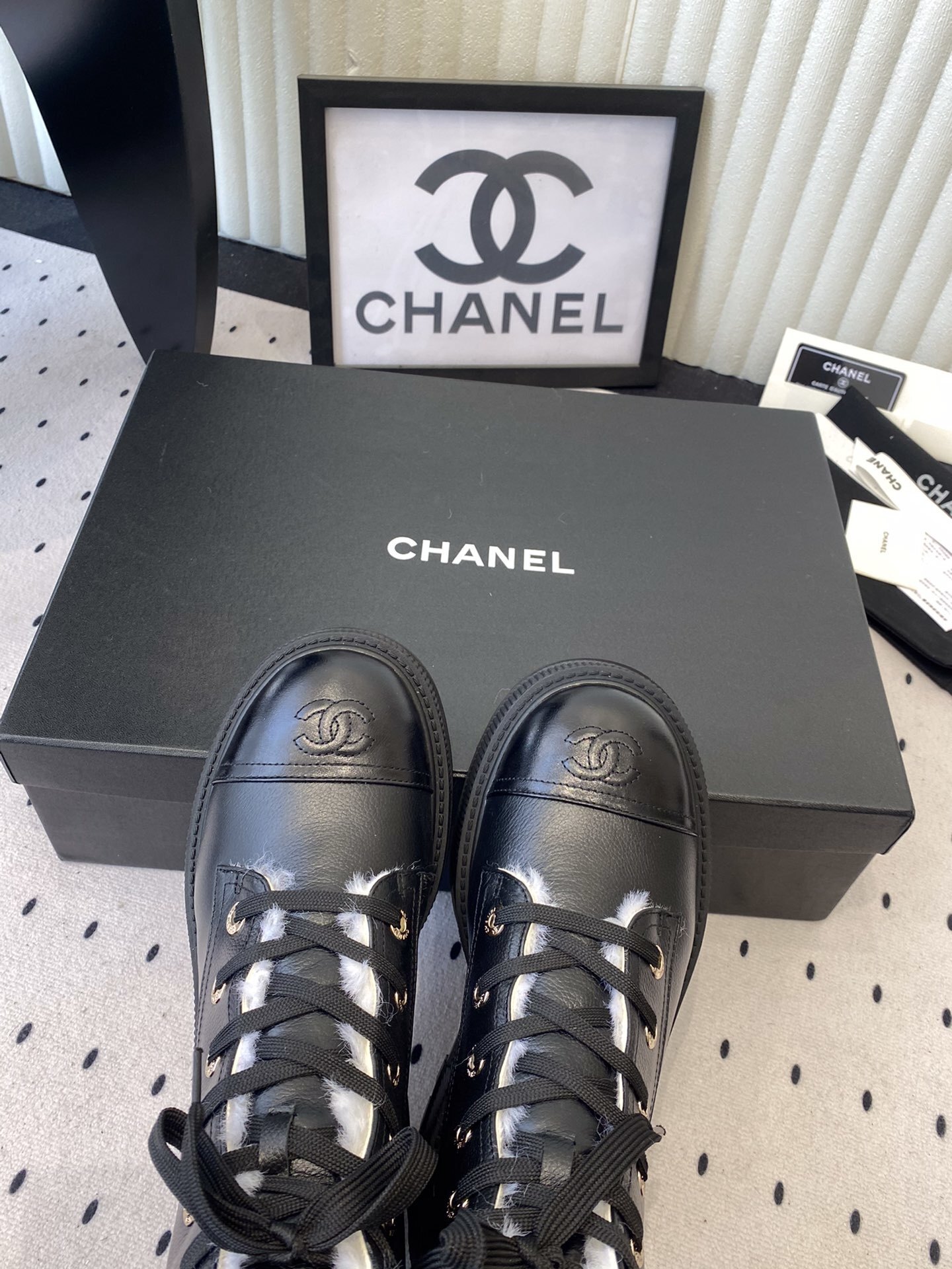 Chanel black leather lace-up combat boots with white shearling lining and gold-tone hardware on a black box. - Hình 4