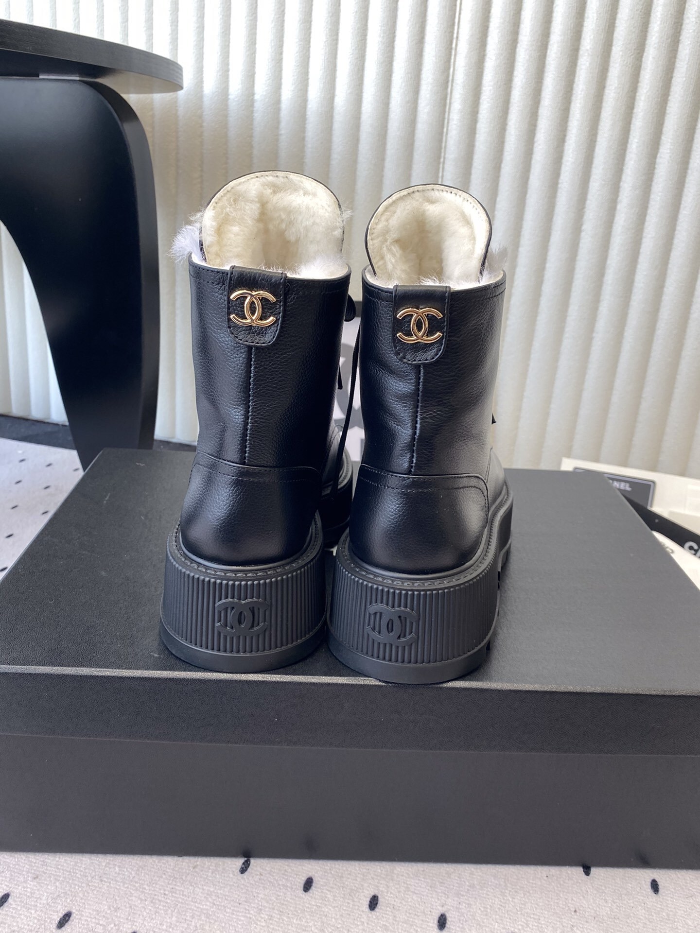 Chanel black leather lace-up combat boots with white shearling lining and gold-tone hardware on a black box. - Hình 3