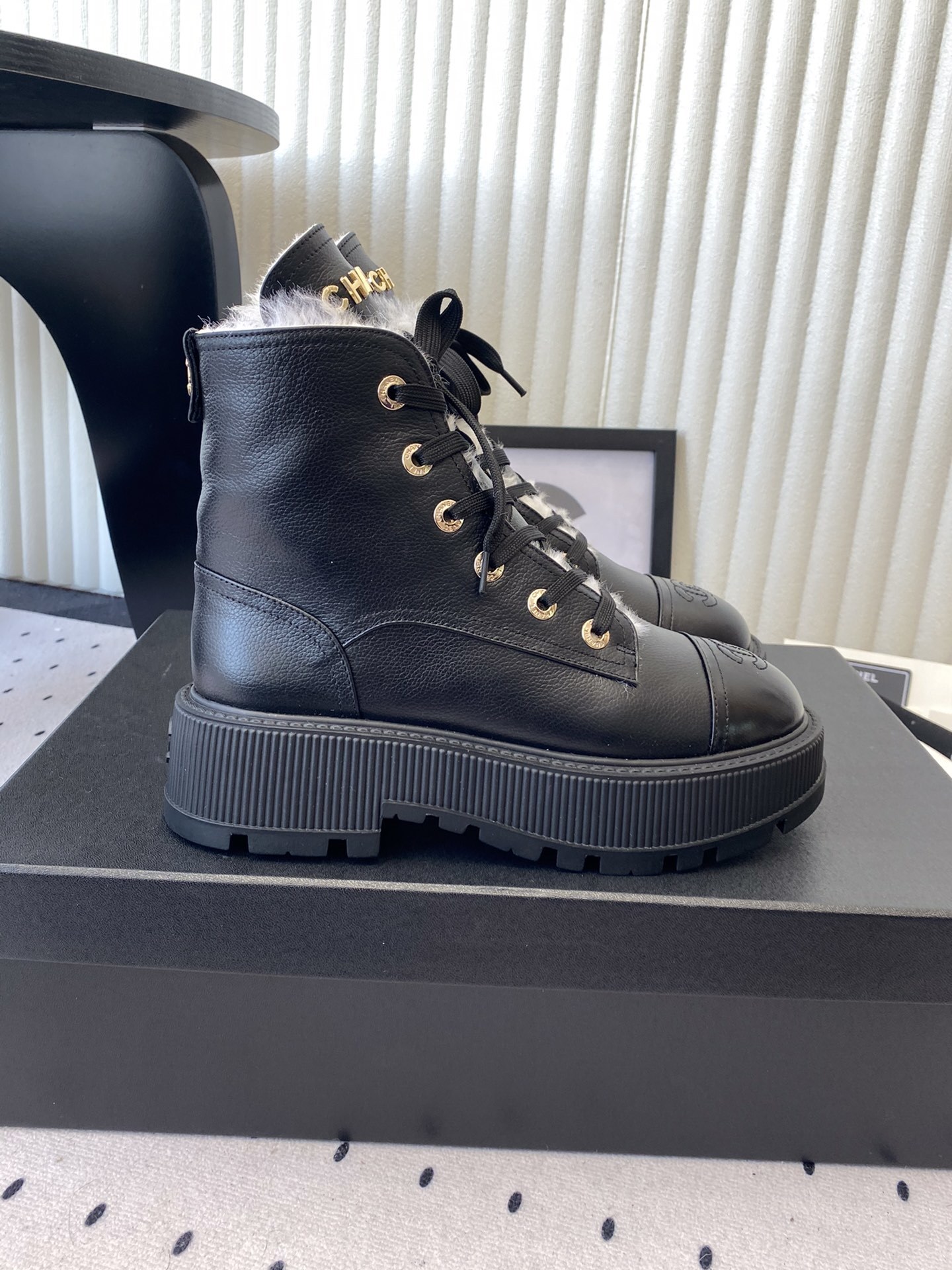 Chanel black leather lace-up combat boots with white shearling lining and gold-tone hardware on a black box. - Hình 2