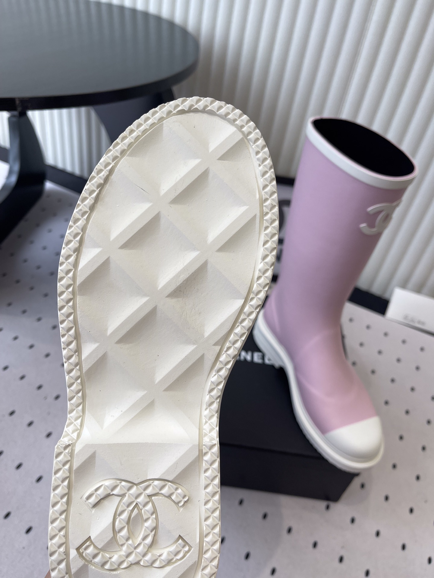 A pair of pastel pink rubber rain boots with white interlocking CC logo and white soles on a black designer box. - Hình 9