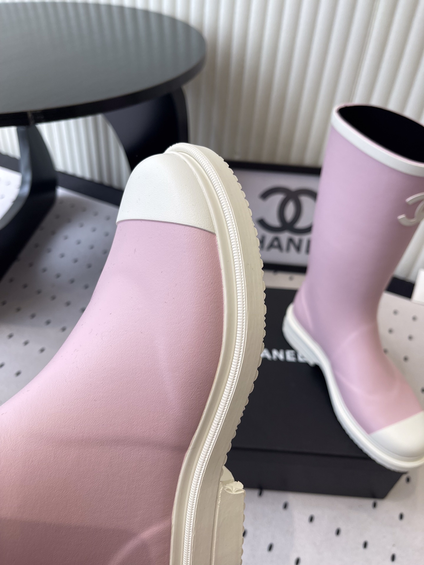 A pair of pastel pink rubber rain boots with white interlocking CC logo and white soles on a black designer box. - Hình 5
