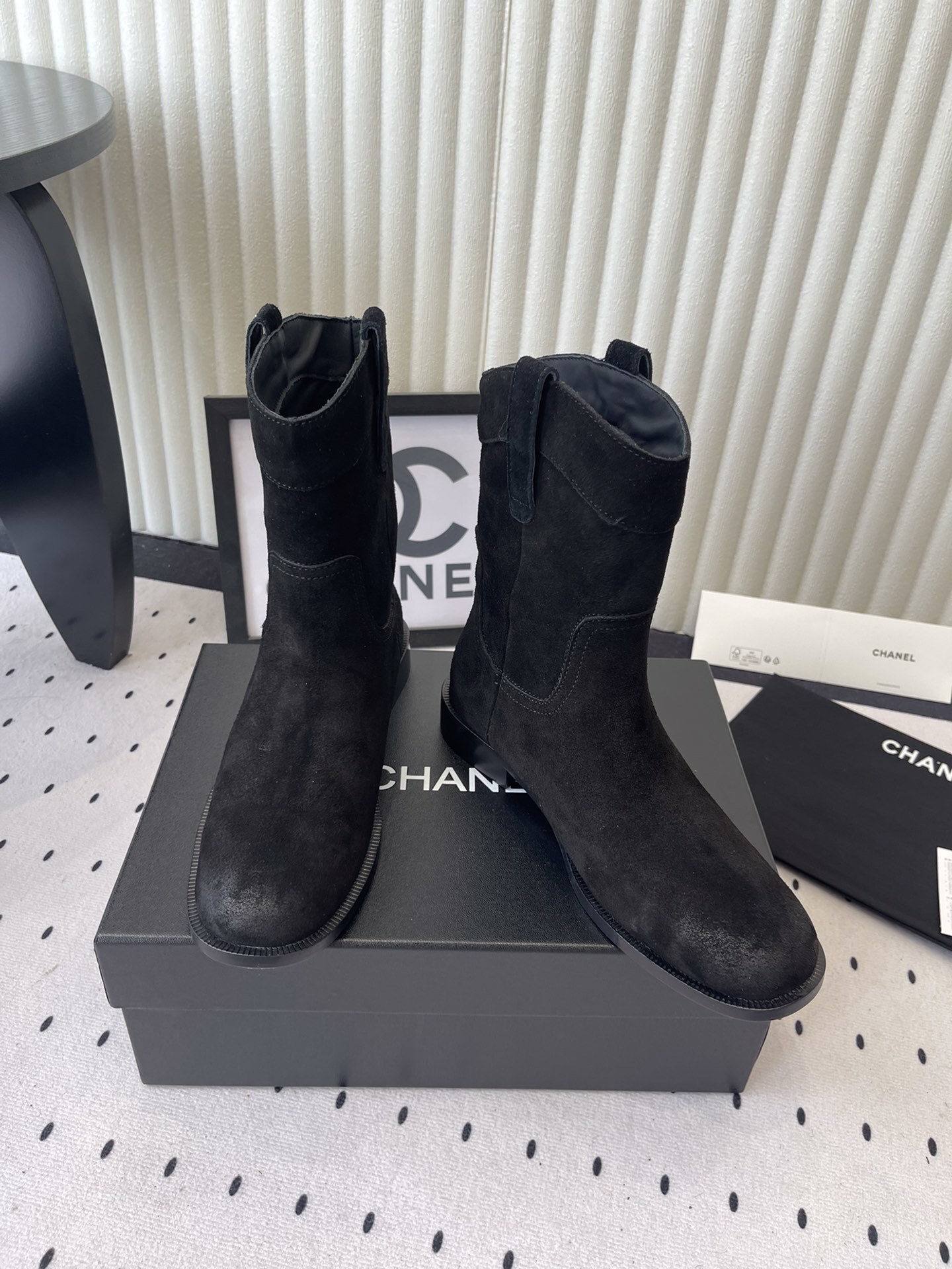 Pair of Chanel black suede mid-calf boots with white logo pull tabs displayed on a black Chanel shoe box - Hình 7