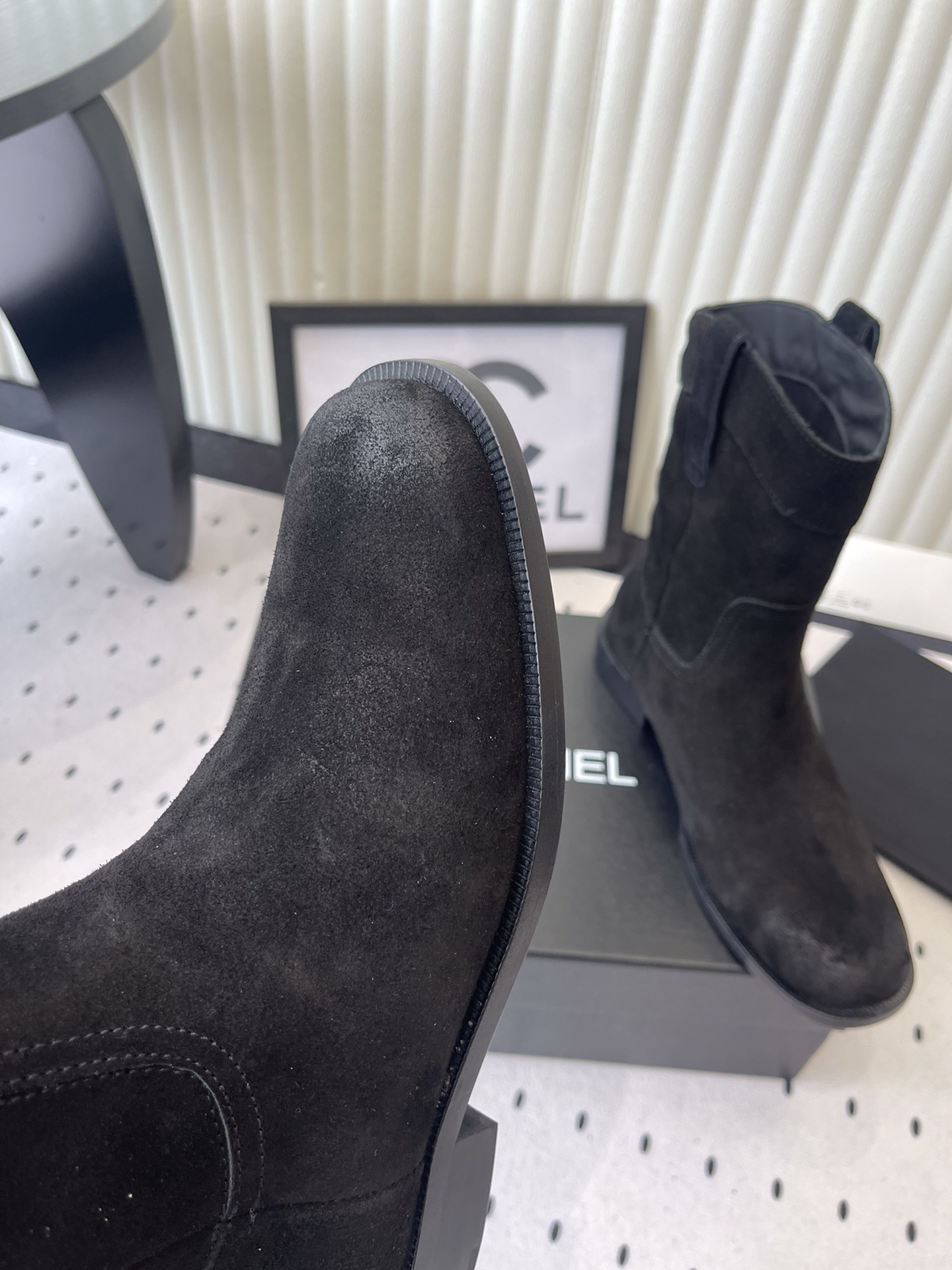 Pair of Chanel black suede mid-calf boots with white logo pull tabs displayed on a black Chanel shoe box - Hình 6