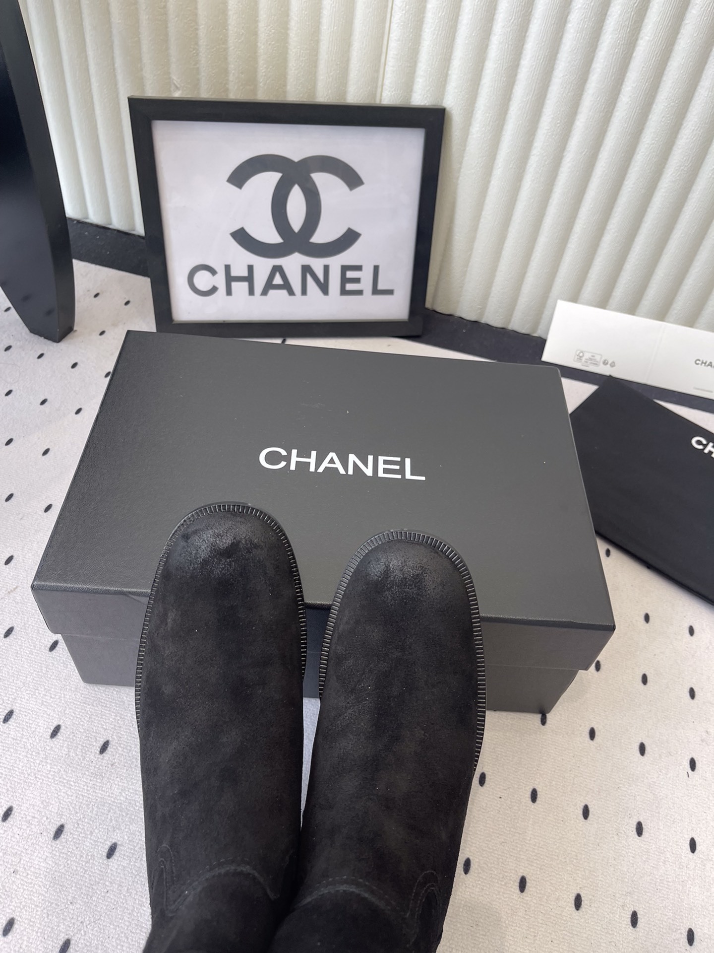 Pair of Chanel black suede mid-calf boots with white logo pull tabs displayed on a black Chanel shoe box - Hình 4