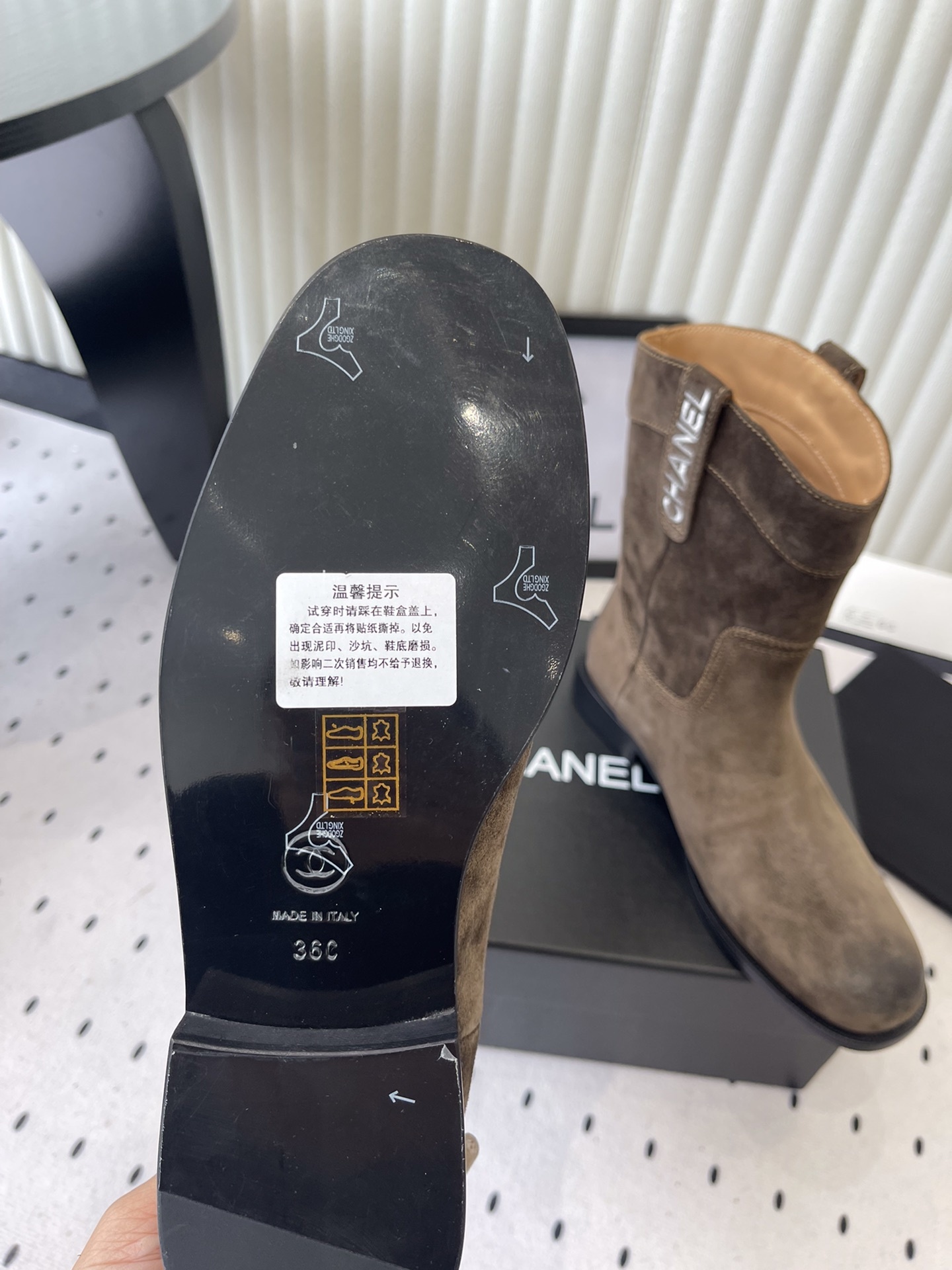 A pair of Chanel brown suede mid-calf Western style boots with embroidered logo pull tabs on a black box. - Hình 9