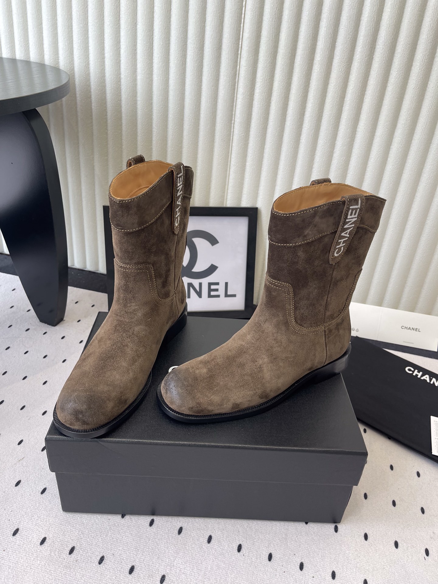 A pair of Chanel brown suede mid-calf Western style boots with embroidered logo pull tabs on a black box. - Hình 8