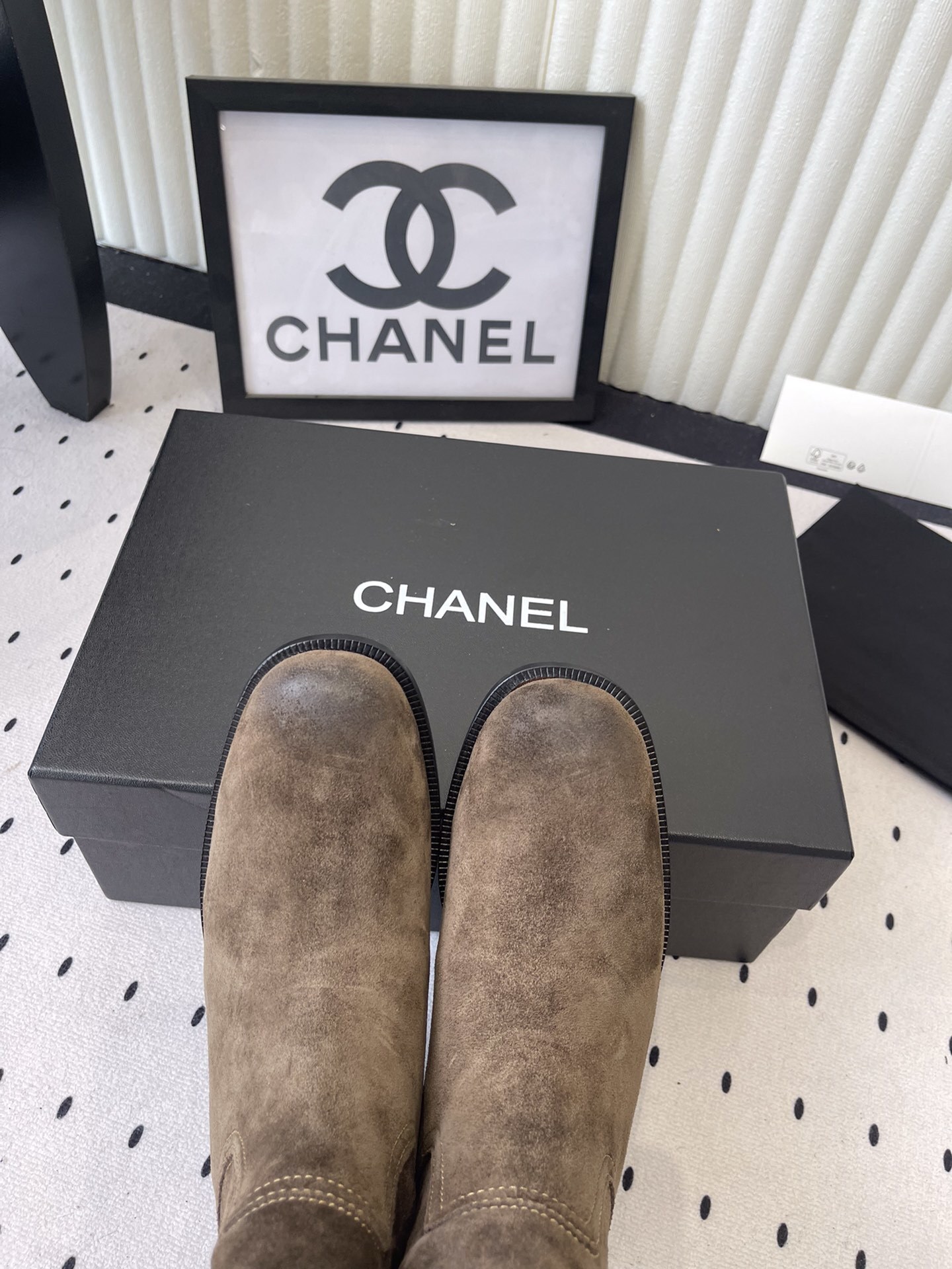 A pair of Chanel brown suede mid-calf Western style boots with embroidered logo pull tabs on a black box. - Hình 4