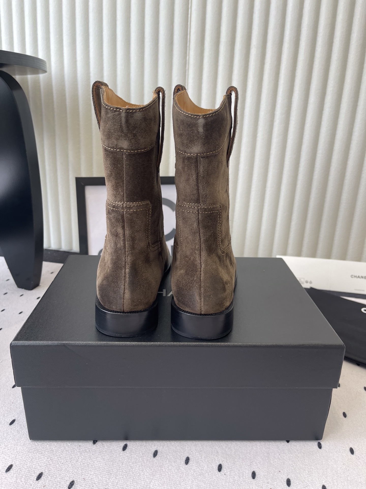 A pair of Chanel brown suede mid-calf Western style boots with embroidered logo pull tabs on a black box. - Hình 3