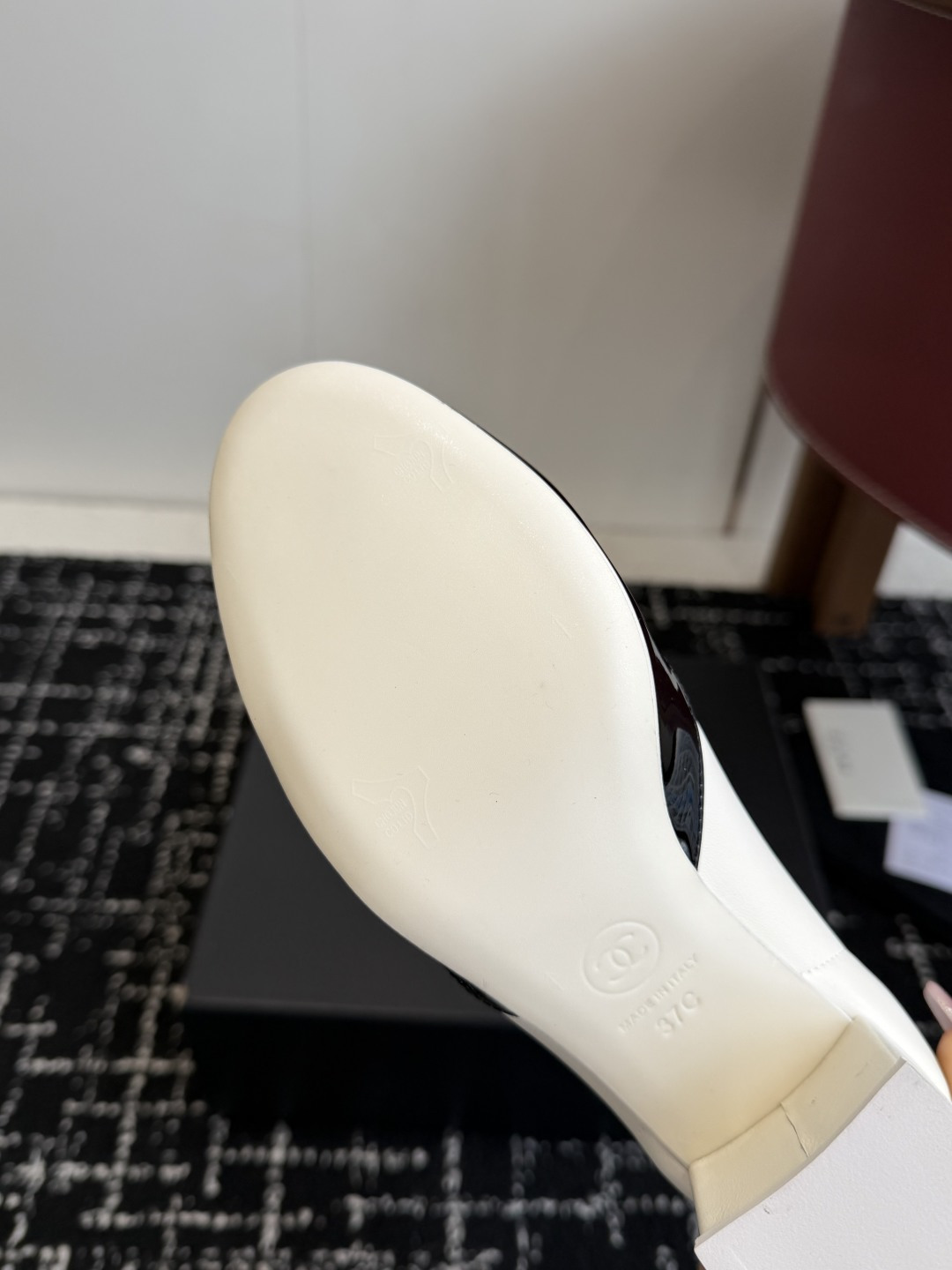 A pair of Chanel white leather ankle boots with black patent leather toe caps and ruffled collars on a black designer box. - Hình 9