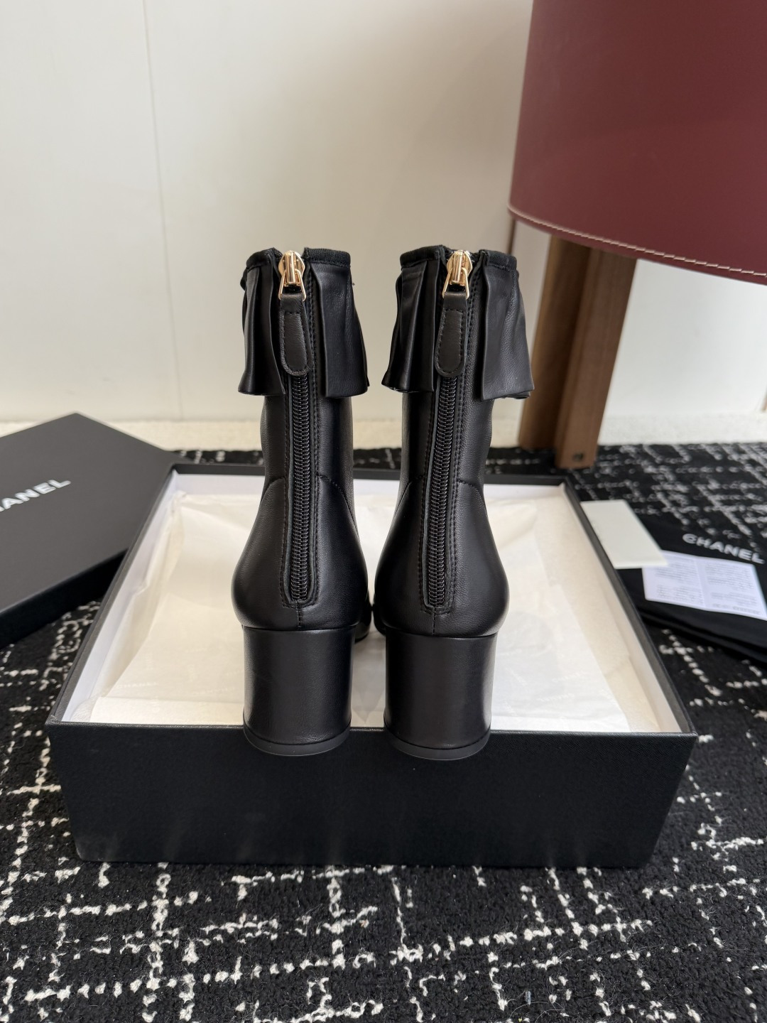 Authentic Chanel black leather ankle boots with ruffle detail and patent toe sitting on a black designer box - Hình 8