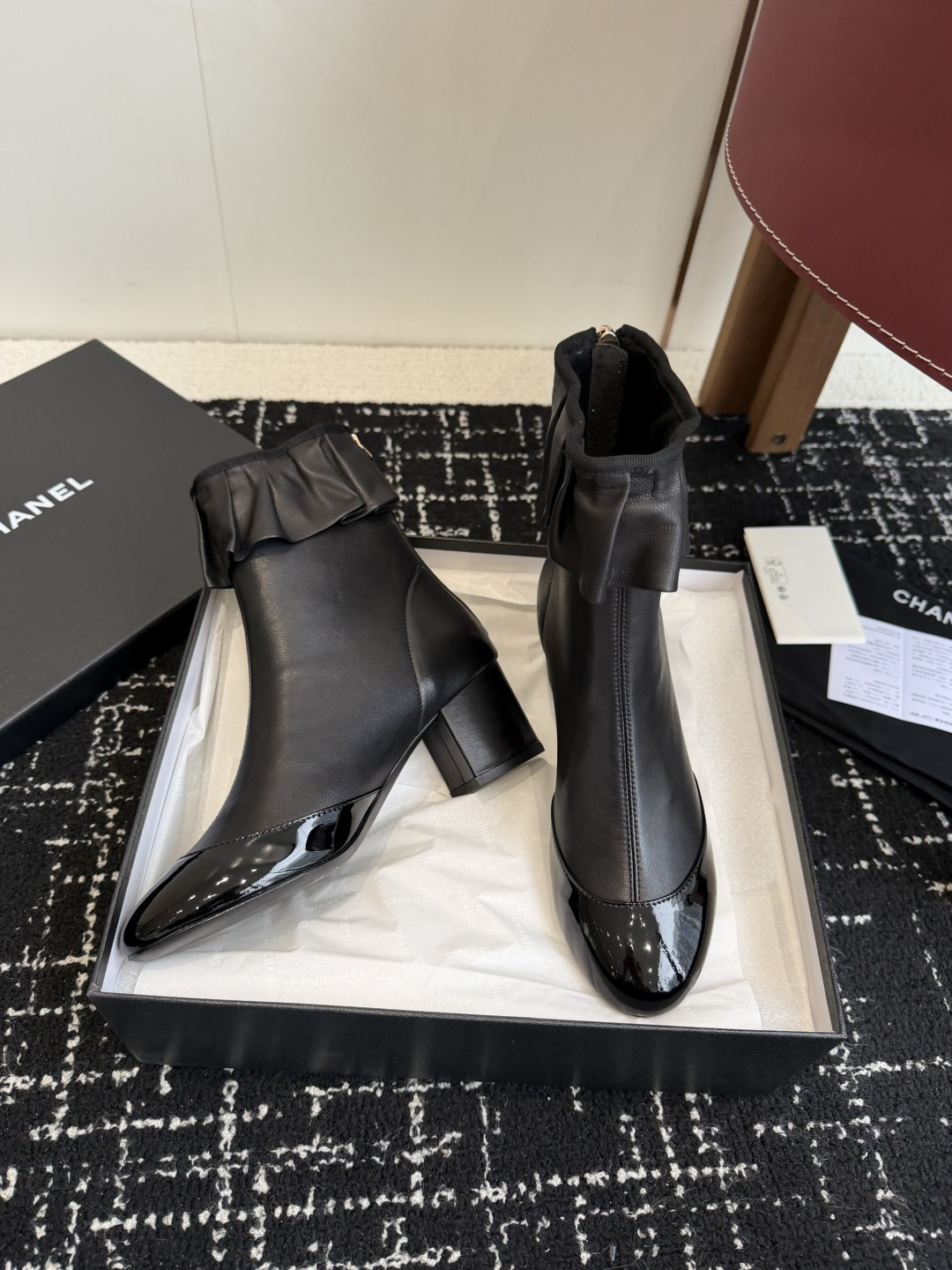 Authentic Chanel black leather ankle boots with ruffle detail and patent toe sitting on a black designer box - Hình 5