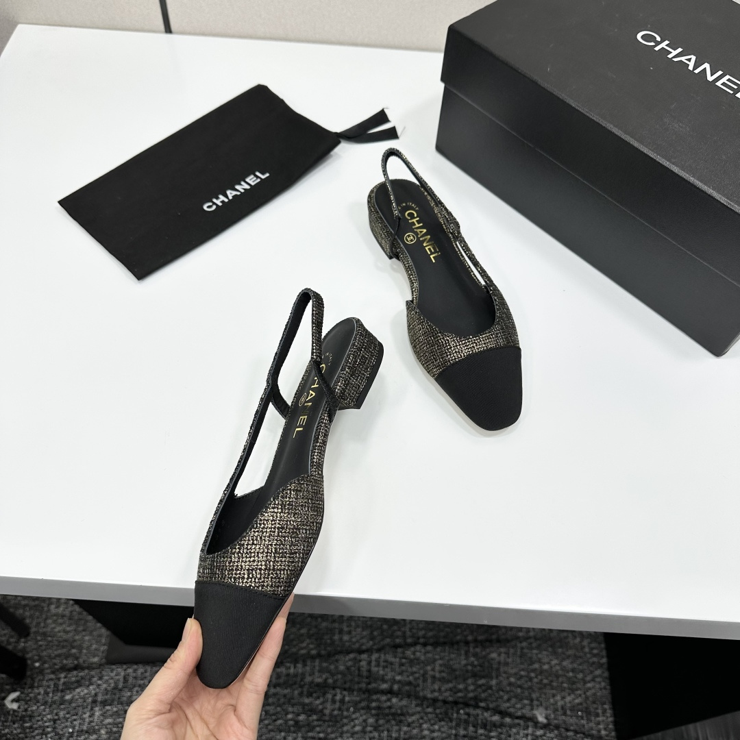 A pair of Chanel gold and black tweed slingback flats with black cap toes displayed on a black designer box. - Hình 10
