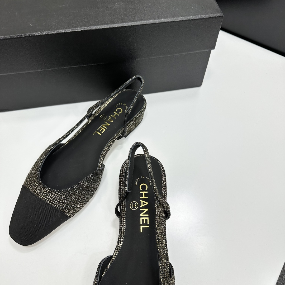 A pair of Chanel gold and black tweed slingback flats with black cap toes displayed on a black designer box. - Hình 8