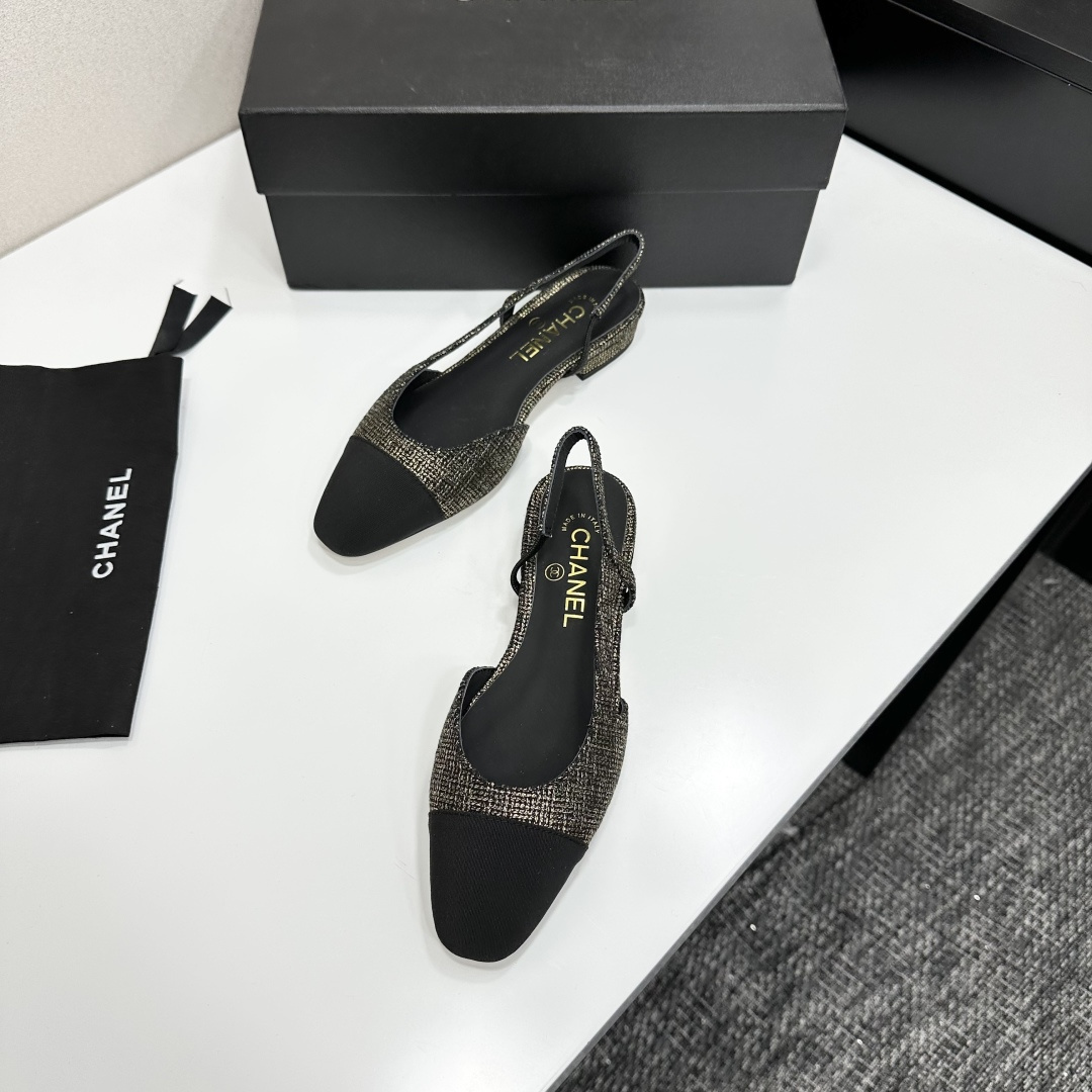 A pair of Chanel gold and black tweed slingback flats with black cap toes displayed on a black designer box. - Hình 6