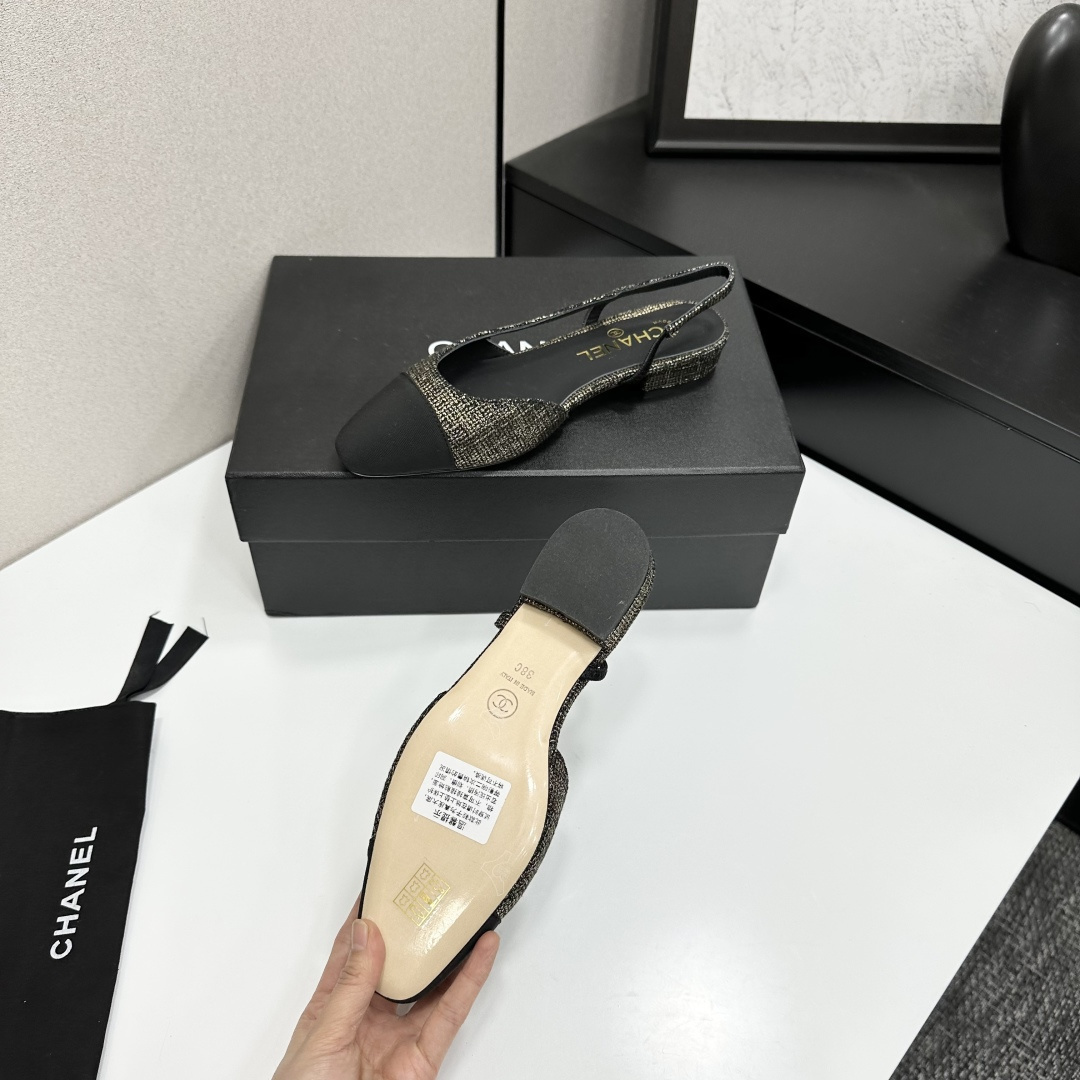 A pair of Chanel gold and black tweed slingback flats with black cap toes displayed on a black designer box. - Hình 5