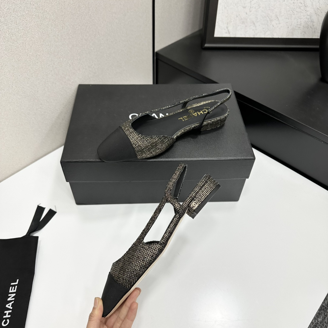 A pair of Chanel gold and black tweed slingback flats with black cap toes displayed on a black designer box. - Hình 4