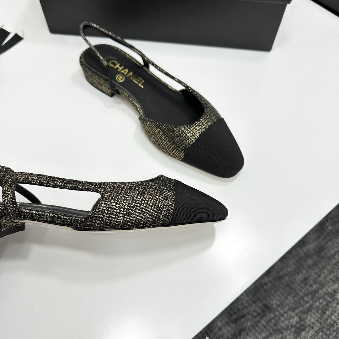 A pair of Chanel gold and black tweed slingback flats with black cap toes displayed on a black designer box. - Hình 2