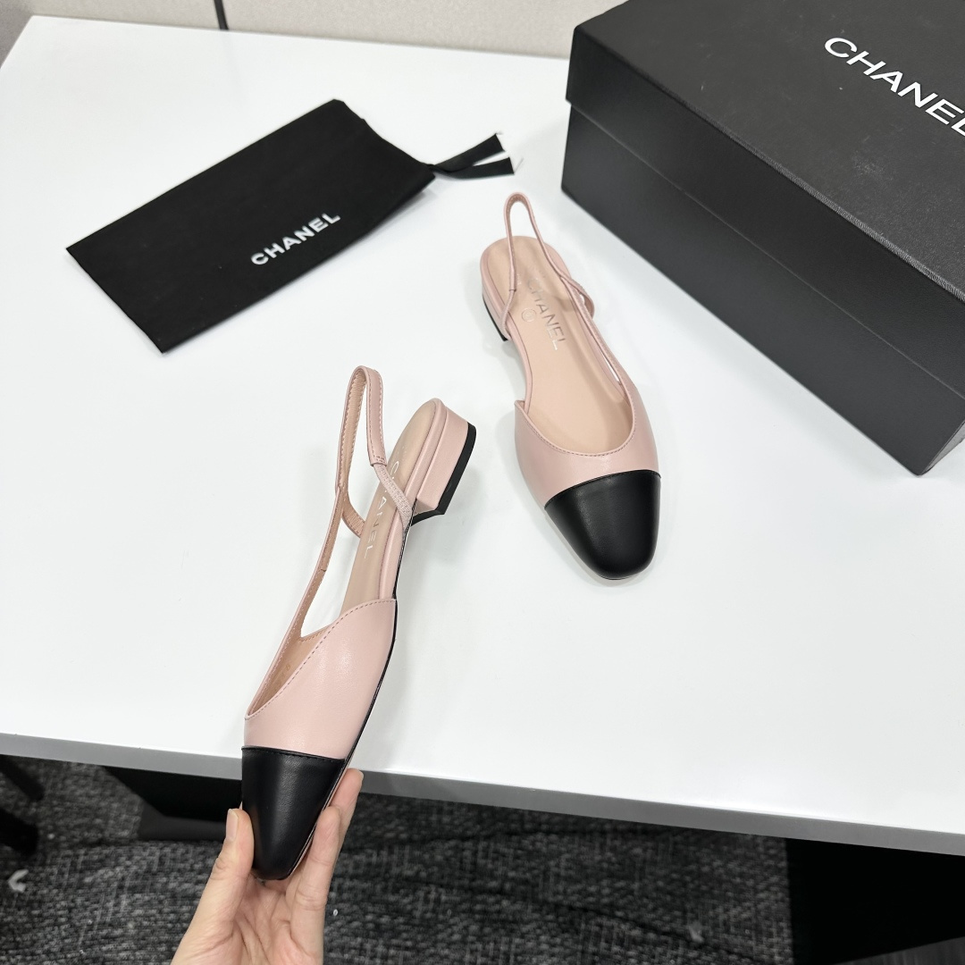 A pair of luxury Chanel pink and black two-tone slingback flats resting on a black designer shoe box. - Hình 9