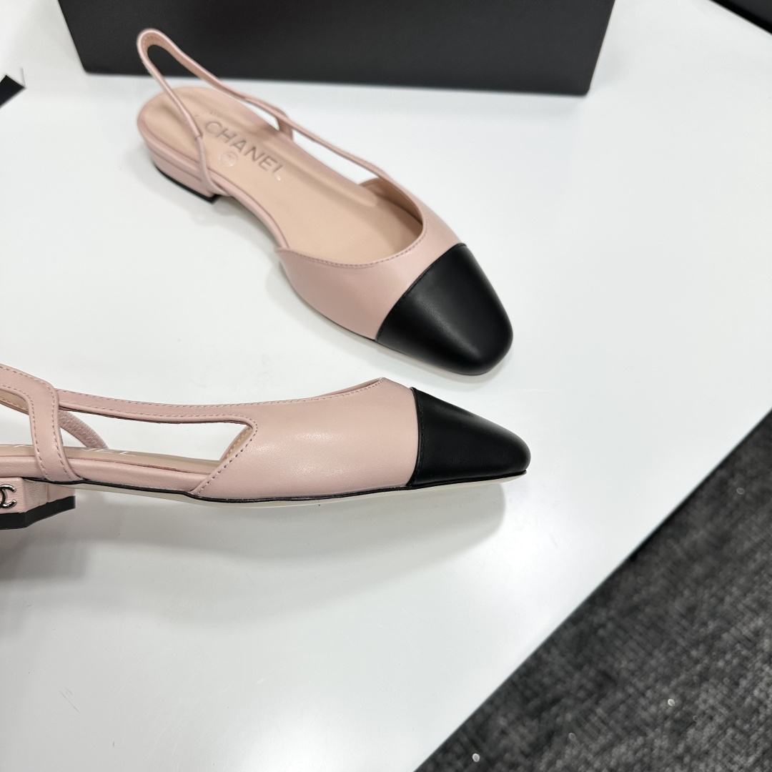 A pair of luxury Chanel pink and black two-tone slingback flats resting on a black designer shoe box. - Hình 2