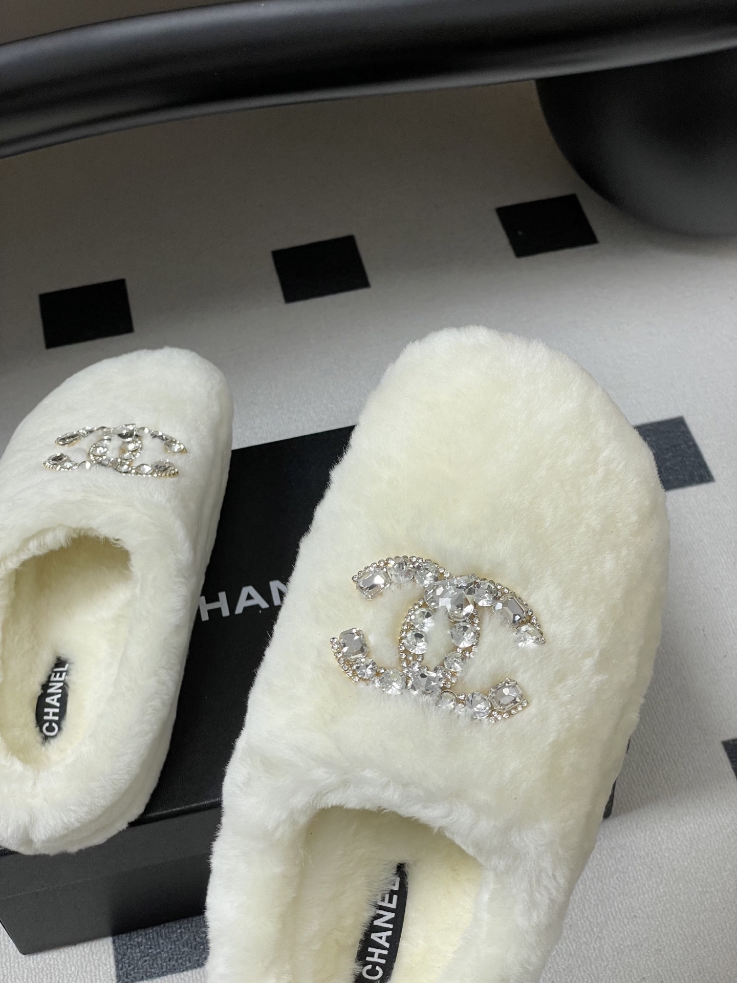 A pair of plush white faux fur slippers featuring a large sparkling crystal encrusted double-C logo on the top. - Hình 9