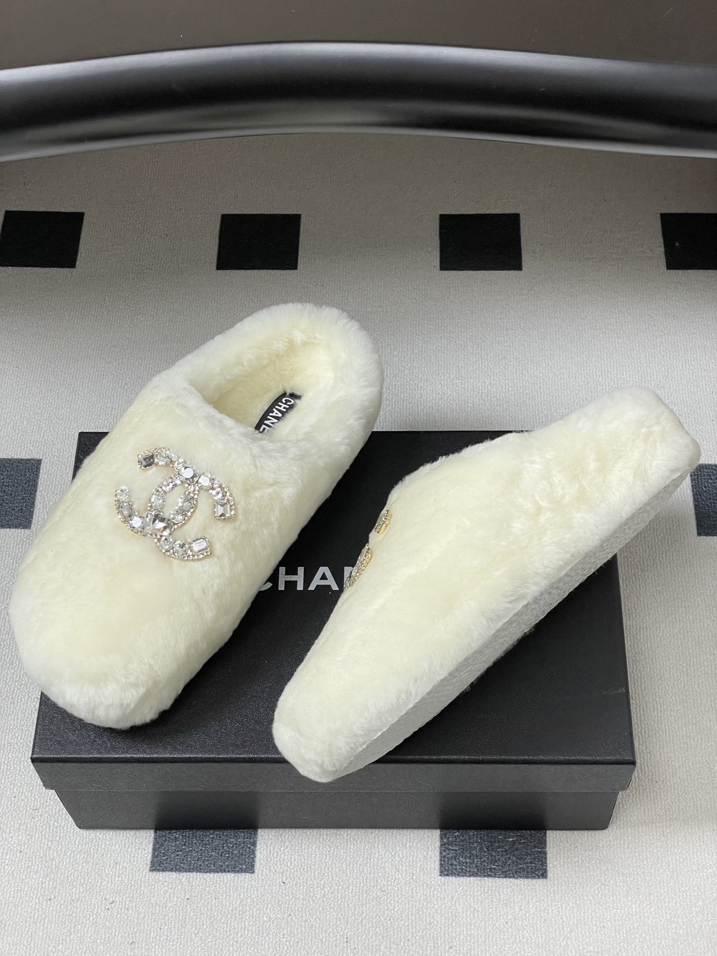 A pair of plush white faux fur slippers featuring a large sparkling crystal encrusted double-C logo on the top. - Hình 4