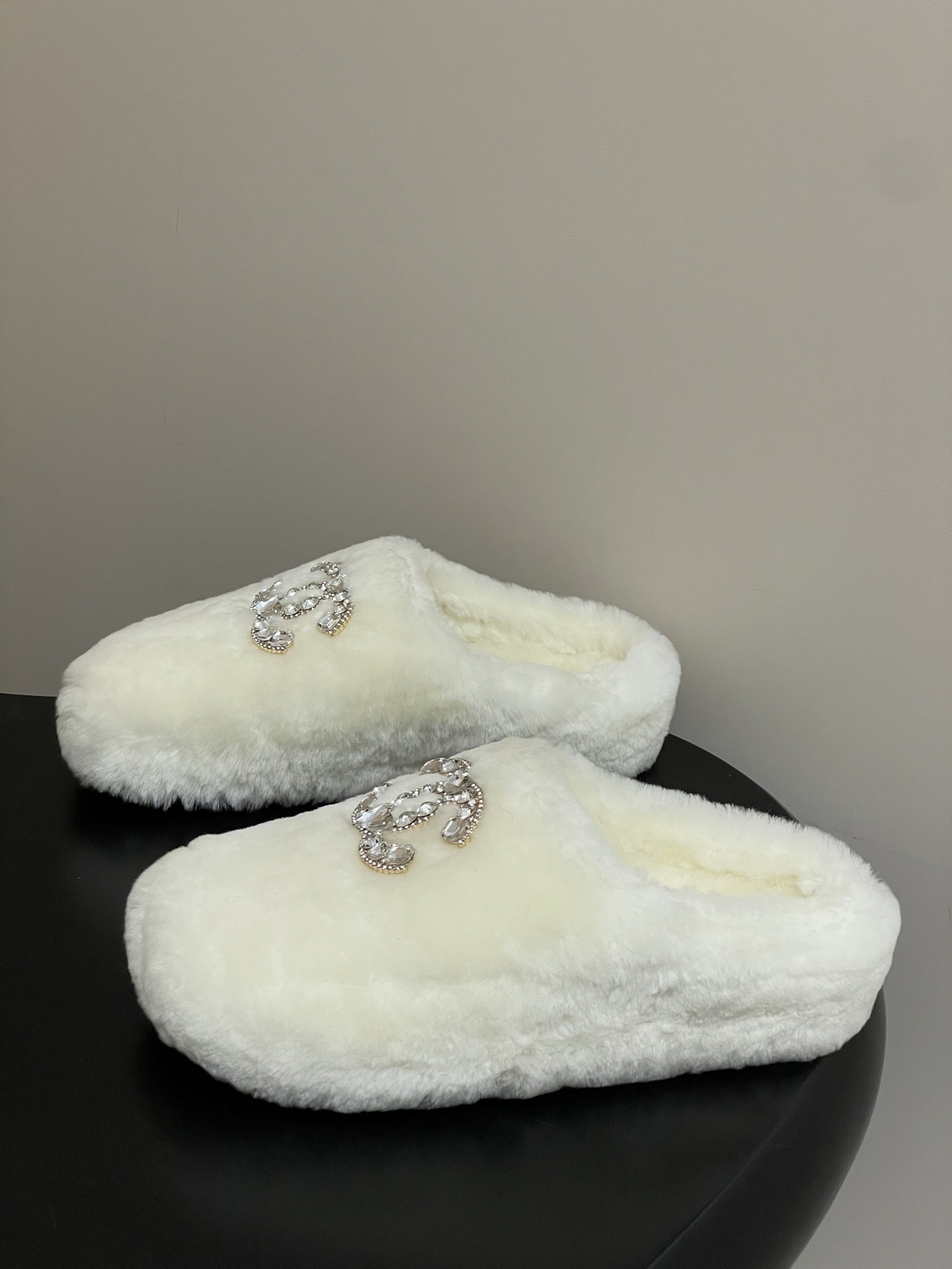 A pair of plush white faux fur slippers featuring a large sparkling crystal encrusted double-C logo on the top. - Hình 3