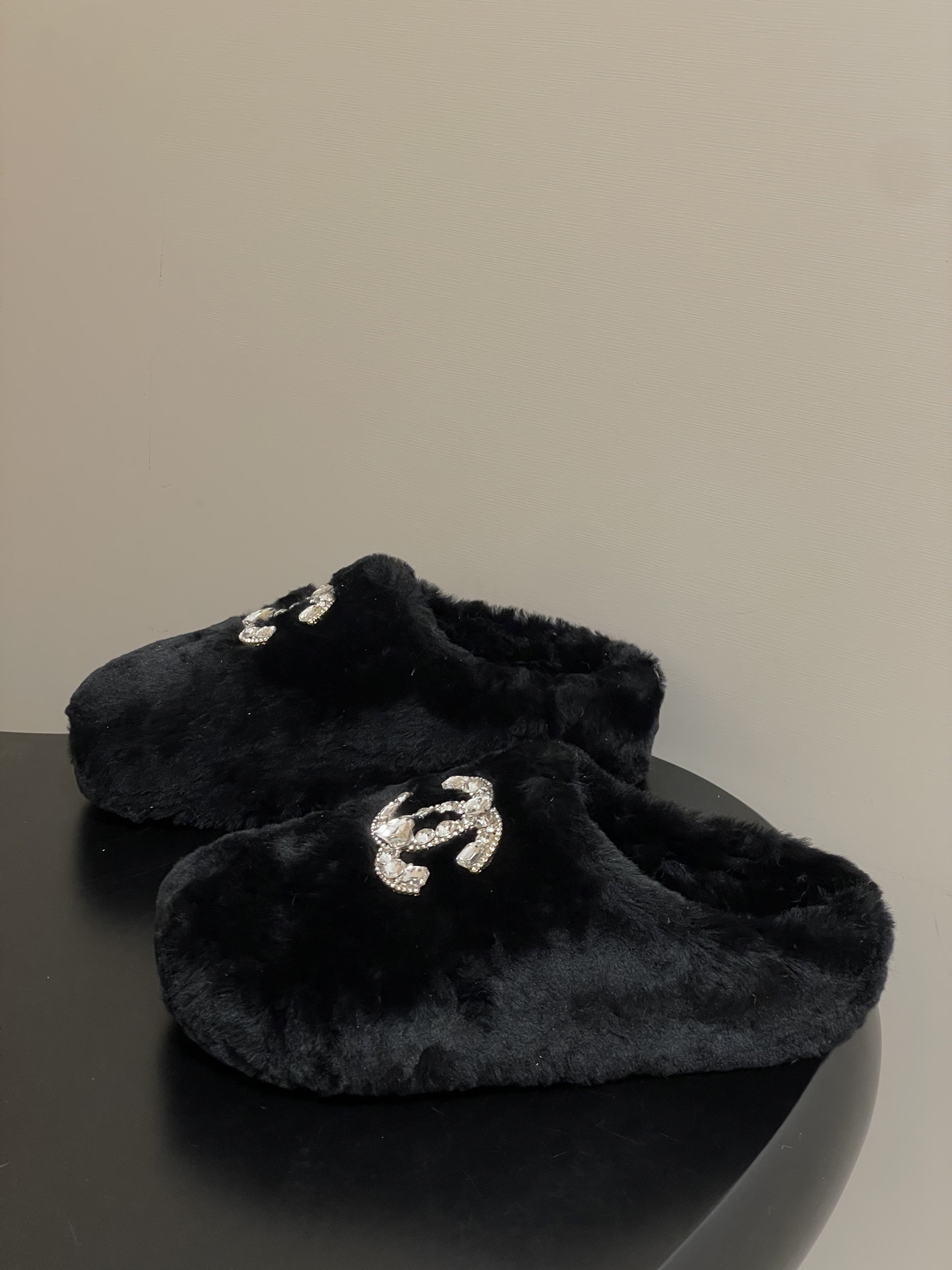 Elegant black fluffy slippers featuring a prominent crystal-studded double-C logo design on a black surface. - Hình 3