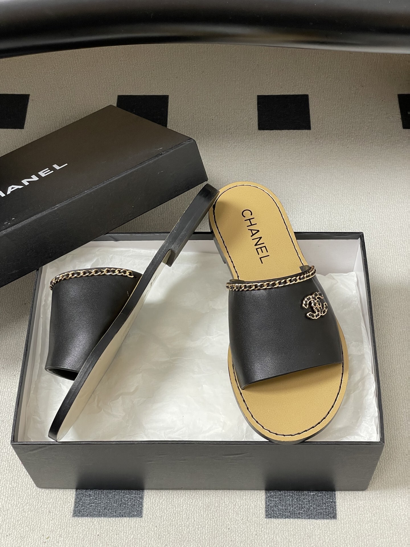 Pair of Chanel black leather flat sandals with gold chain trim and interlocking CC logo on a black surface - Hình 6