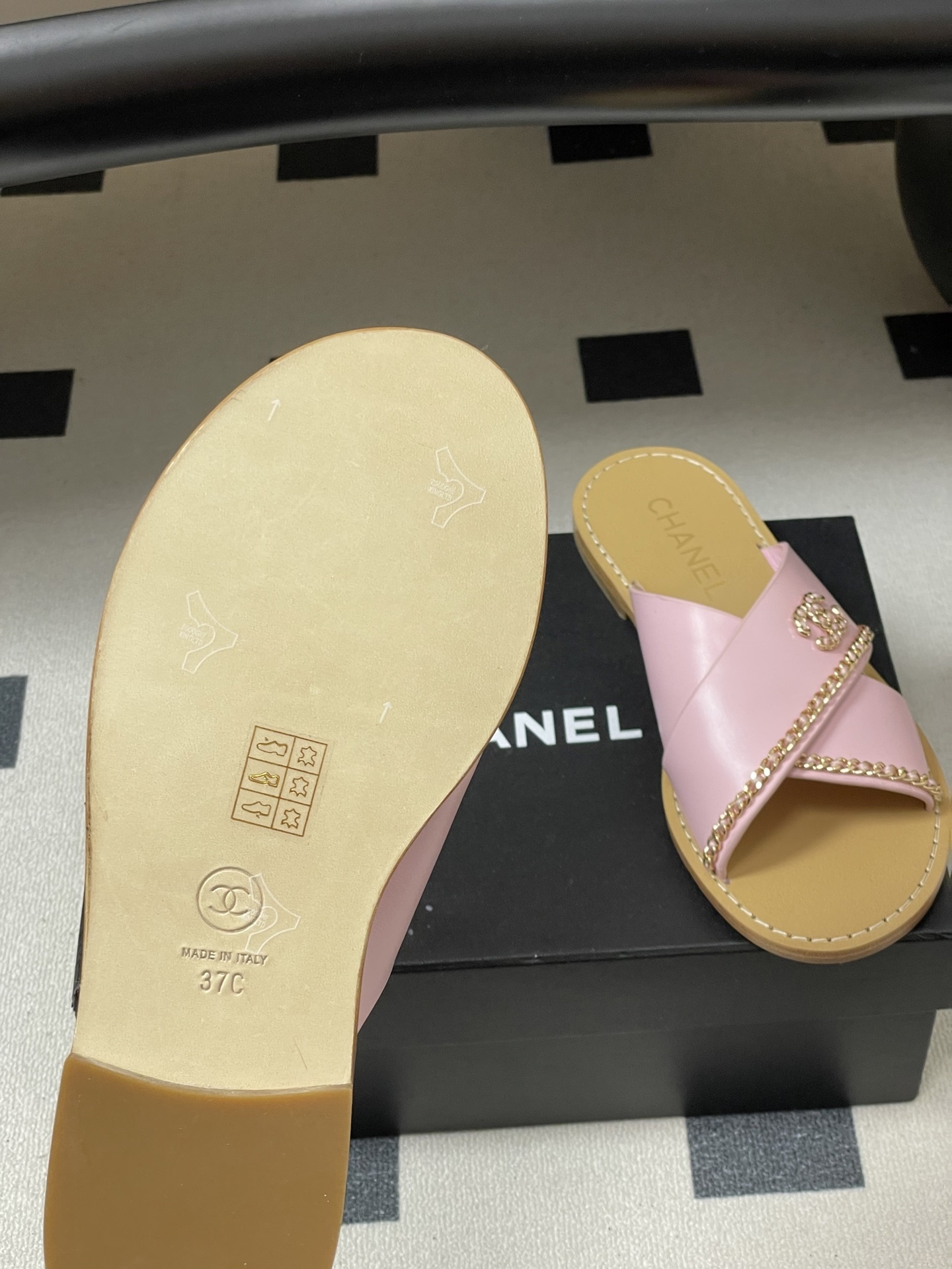 Pair of Chanel light pink leather criss-cross sandals with gold chain detail and CC logo on a black surface - Hình 8